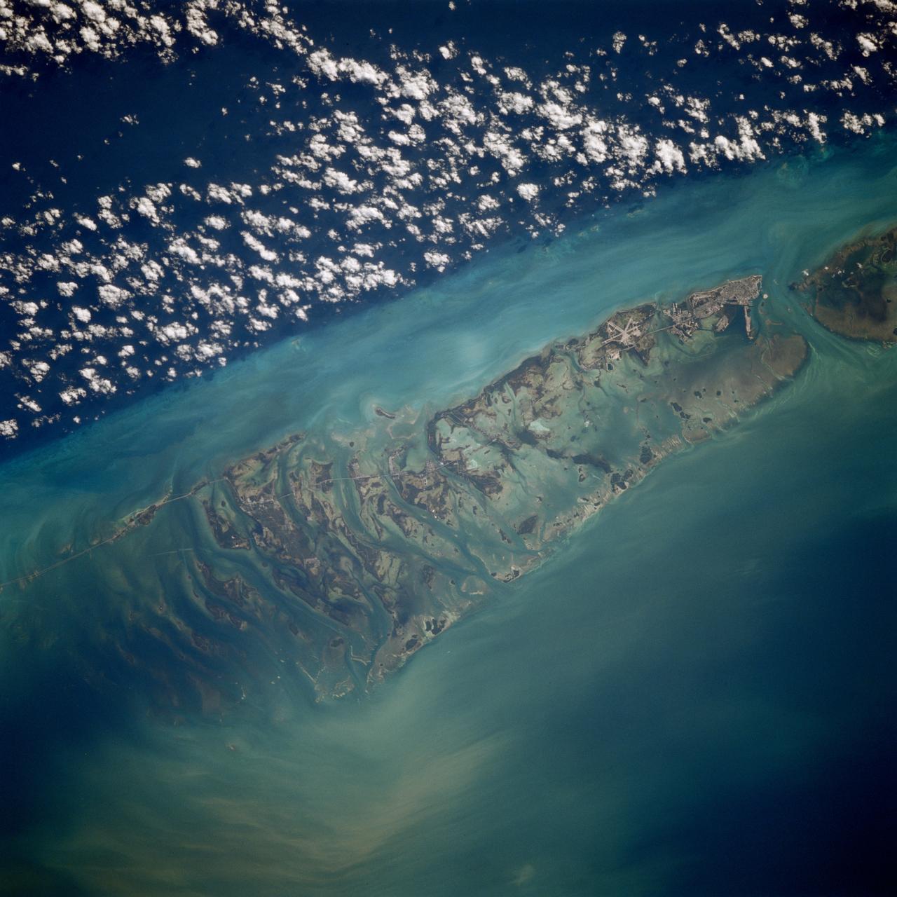 STS080-709-094 (19 Nov.-7 Dec. 1996) --- This is a view of the western portion of the Florida Keys.  The view shows the city of Key West, bottom mid-right, with Marathon Key, near top middle left, and the edge of the Straits of Florida, the dark water on the right edge.  Clouds form over the cooler waters of the strait.  The runways at Boca Chica Key Naval Air Station are seen near Key West.  The bottom can be seen clearly in the shallow water, the deeper water has depths of over a half a mile.  The thin line of the Overseas Highway can be traced east from Key West.  Prior to a hurricane in 1935, this route was a railway line.