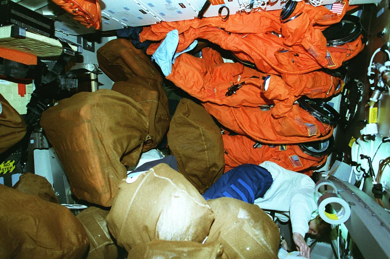 STS081-308-032 (12-22 Jan. 1997) --- Astronaut Marsha S. Ivins appears almost lost among the bags of material to be brought back to Earth at the impending conclusion of the Space Shuttle Atlantis and Russia's Mir Space Station docking mission. Several partial pressure garments which were used for launch and will soon be donned for the entry phase are in upper left.