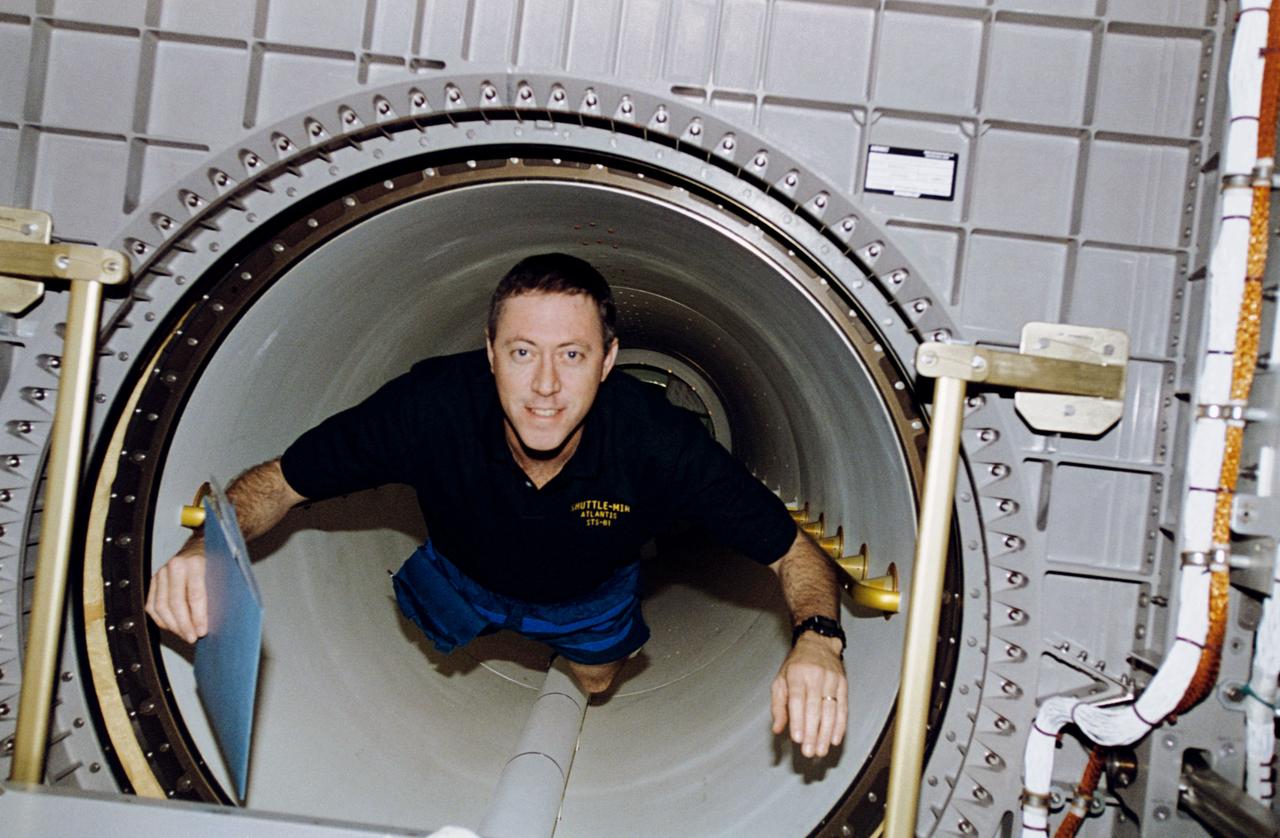 STS081-314-019 (12-22 Jan 1997) --- Astronaut Michael A. Baker, mission commander, floats through the tunnel leading from the Space Shuttle Atlantis mid-deck into Spacehab Double Module (DM). For a period of five days, seven astronauts and two Russian cosmonauts are sharing a variety of chores in space as the spacecraft from their respective nations are docked in Earth-orbit.