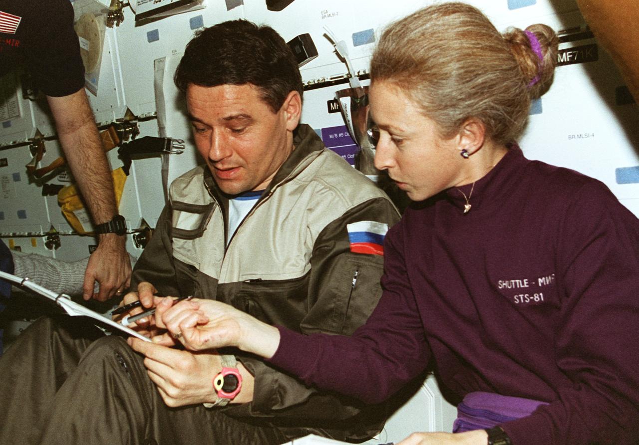 STS081-357-020 (12-22 Jan. 1997) --- Astronaut Marsha S. Ivins, STS-81 mission specialist, compares notes with cosmonaut Valeri G. Korzun, Mir-22 mission commander. The two were involved with the transfer of supplies from the Space Shuttle Atlantis to Russia's Mir Space Station, during the docking mission.