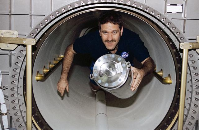 NASA image: MS Grunsfeld moves freezer unit through transfer tunnel to Spacehab