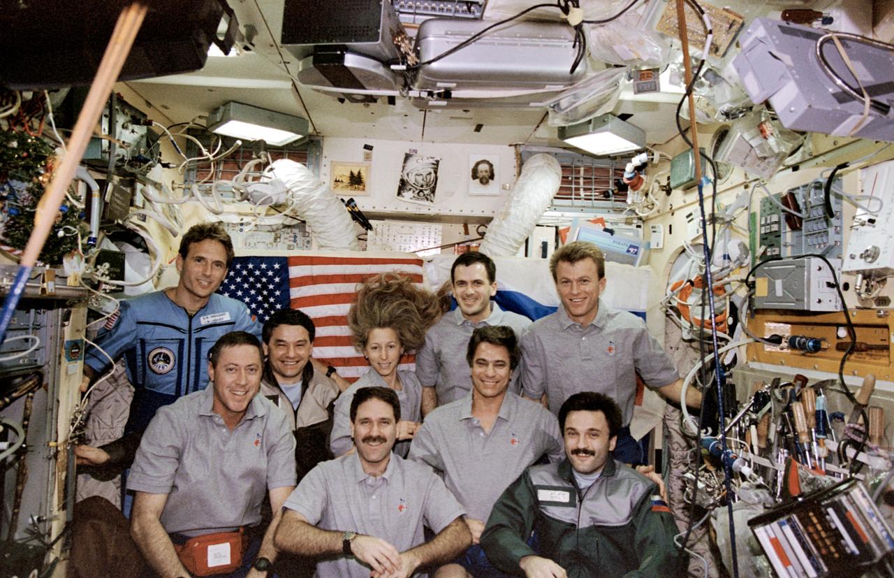 STS081-369-003 (12-22 Jan. 1997) --- Traditional inflight crew portrait of the combined Mir-22 and STS-81 crews in the Base Block Module aboard Russia's Mir Space Station. Front row: left to right, Michael A. Baker, commander; John M. Grunsfeld, mission specialist; and cosmonaut Aleksandr Y. Kaleri, Mir-22 flight engineer. Middle row: cosmonaut Valeri G. Korzun, Mir-22 commander; Marsha S. Ivins, mission specialist; and John E. Blaha, former cosmonaut guest researcher. Back row: Jerry M. Linenger, cosmonaut guest researcher; Peter J. K. (Jeff) Wisoff, mission specialist; and Brent W. Jett, Jr., pilot. Linenger is seen in a Russian jump suit, and Blaha now wears a Space Shuttle inflight garment as the two exchanged cosmonaut guest researcher roles on January 14, 1997, following the docking of the Atlantis and the Mir complex.