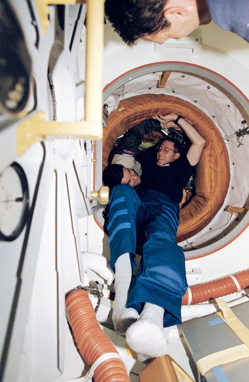STS081-373-025 (14 Jan 1997) --- Greeting between commanders - astronaut Michael A. Baker (foreground) and cosmonaut Valeri G. Korzun - just after hatch opening following the January 14, 1997, docking.  Out of frame on the Space Shuttle Atlantis is astronaut Jerry M. Linenger, soon to be trading places with John E. Blaha, the current cosmonaut guest researcher, onboard Russia?s Mir Space Station since mid September 1996.  Along with Baker and Linenger, other crew members now aboard Atlantis are astronauts Brent W. Jett, Jr., pilot; and mission specialists John M. Grunsfeld, Marsha S. Ivins and Peter J. K. (Jeff) Wisoff.