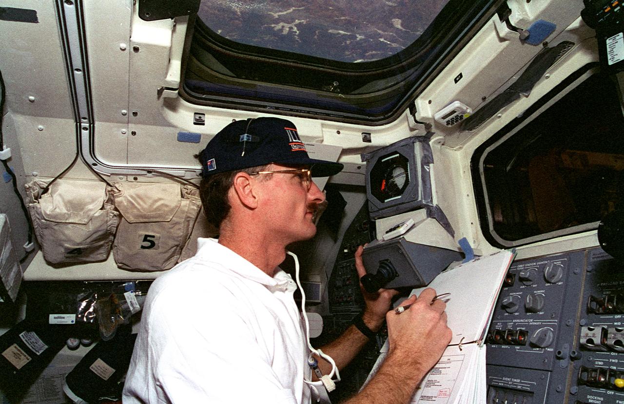 STS082-317-003 (11 -21 Feb. 1997) --- Astronaut Joseph R. Tanner, one half of a space walk team on mission STS-82 to service the Hubble Space Telescope (HST), watches the Extravehicular Activity (EVA) of another team from Discovery's aft flight deck.  Through Discovery's overhead window, lakes and a timber area appear almost close enough for Tanner to touch.