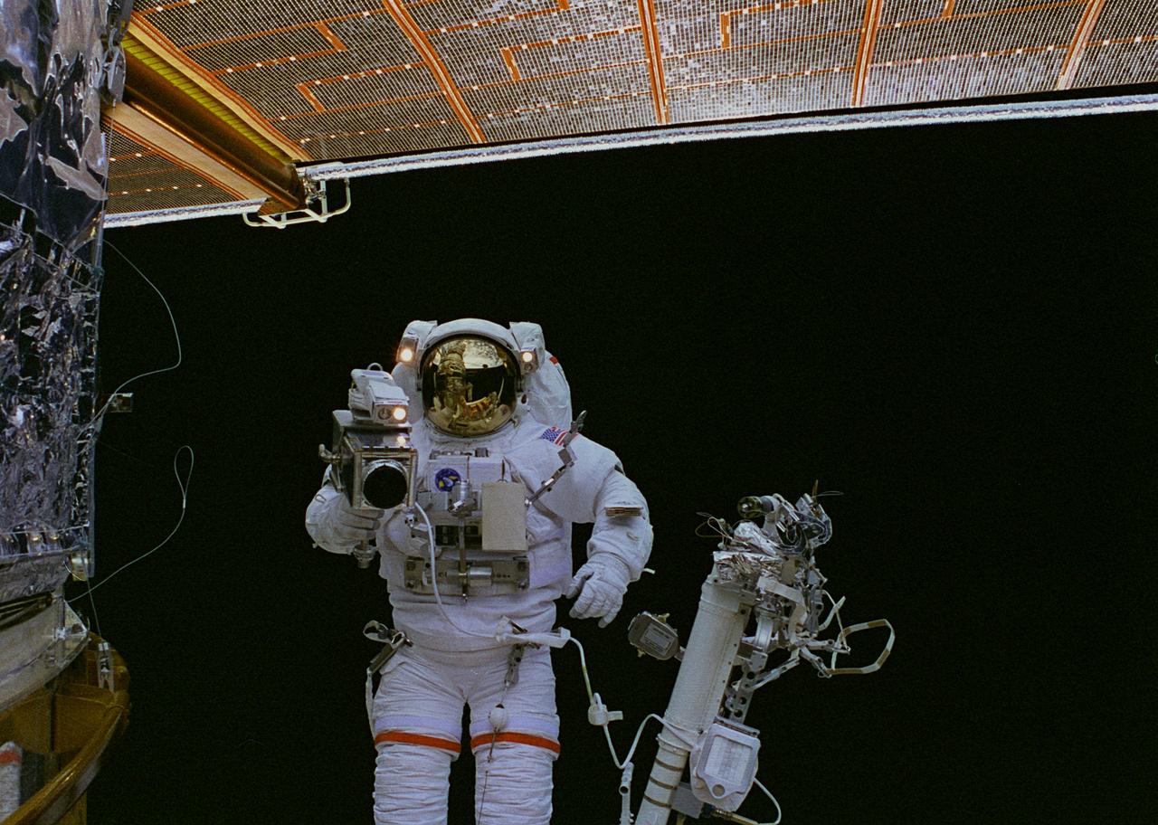 STS082-323-017 (17 Feb. 1997) --- Astronaut Mark C. Lee, on the end of the Remote Manipulator System (RMS) arm, photographs a bit of patch work on the worn insulation material of the Hubble Space Telescope (HST). The rectangular patch is on HST's Bay 8.  Astronaut Steven L. Smith (out of frame) assisted with the patch work.  This was the final Extravehicular Activity (EVA) of five performed by two teams of space walkers on the STS-82 crew.