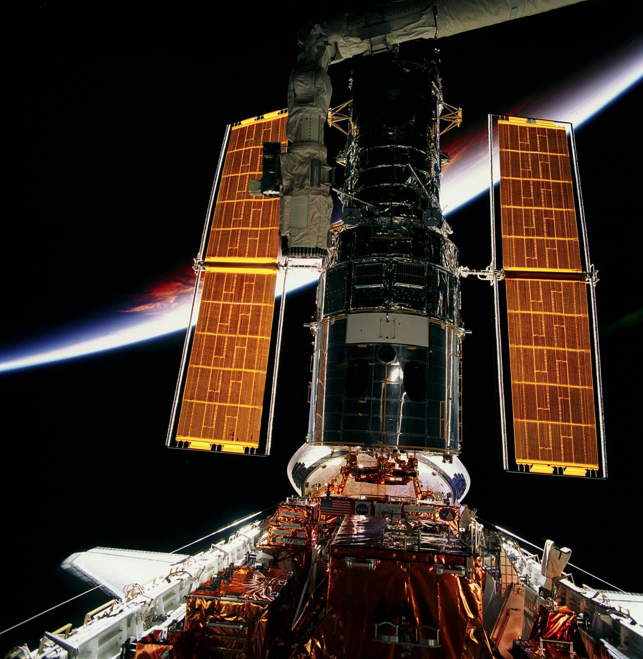 STS082-703-051 (11-21 Feb. 1997) --- In Discovery's cargo bay, the Hubble Space Telescope (HST) is backdropped against Earth's limb and atmosphere following its servicing by astronauts and prior to its release.  Two teams of space walkers alternated Extravehicular Activity (EVA) days to complete five total days of servicing chores on the orbiting observatory.
