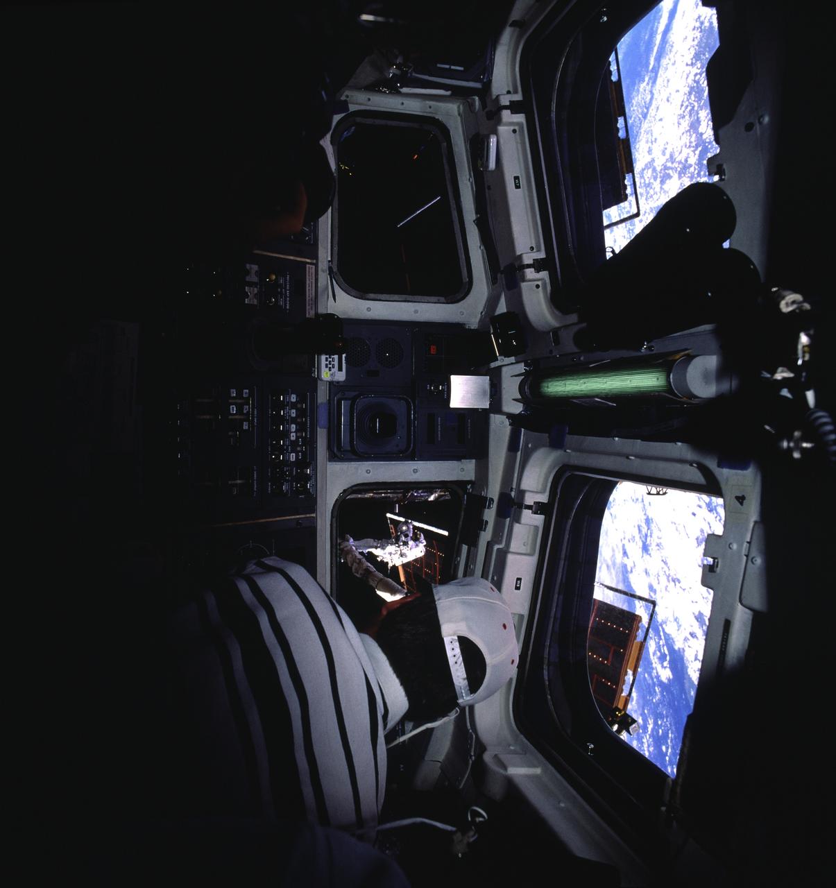 STS082-711-094 (11-21 Feb. 1997) --- From inside the crew cabin, astronaut Steven A. Hawley watches the Extravehicular Activity (EVA) of astronaut Mark C. Lee, payload commander, visible in the background through one of the Space Shuttle Discovery's aft flight deck windows.  Actually, Hawley is doing more than watching the EVA to perform servicing work on the Hubble Space Telescope (HST).  For most of the five days of EVA, Hawley, a veteran of the April 1990 flight which deployed the giant orbiting observatory, controlled the Remote Manipulator System (RMS), on which Lee is standing in this scene.