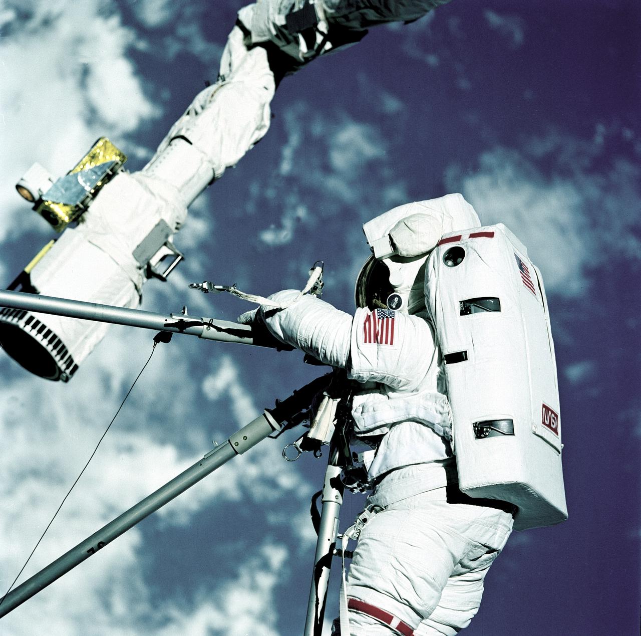 STS082-717-029 (11-21 Feb. 1997) --- Astronauts Mark C. Lee, STS-82 payload commander, (bottom), and Steven L. Smith, mission specialist, handle Hubble Space Telescope (HST) replacement parts during Extravehicular Activity (EVA) on Flight Day 4. The two were participating in the first of five eventual days of EVA to service the giant orbital observatory. Smith is standing on the end of the Remote Manipulator System (RMS) arm, which was controlled by astronaut Steven A. Hawley inside the Space Shuttle Discovery's crew cabin.