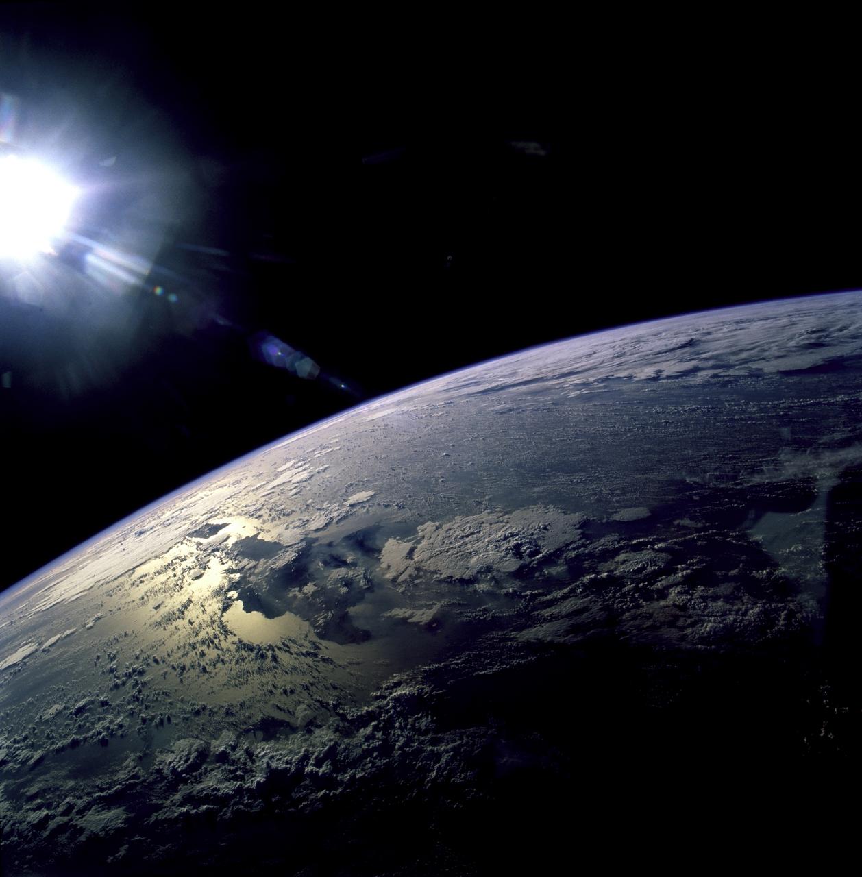 STS082-723-071 (11-21 Feb. 1997) --- The island of Hispaniola appears left center in this wide-angle view, photographed with a 70mm handheld camera from the Earth-orbiting Space Shuttle Discovery. The prominent cape is Cap-a-Foux, the northwest point of Haiti.  The cloud is broken by the mountainous spine of the island. Smoke from bush fires appears in the valleys between the ridges. The coppery tinge of light reflected off the sea surface indicates pollution in the air -- probably industrial pollutants from North America which are typically fed around from the Atlantic seaboard into the Caribbean from the east.