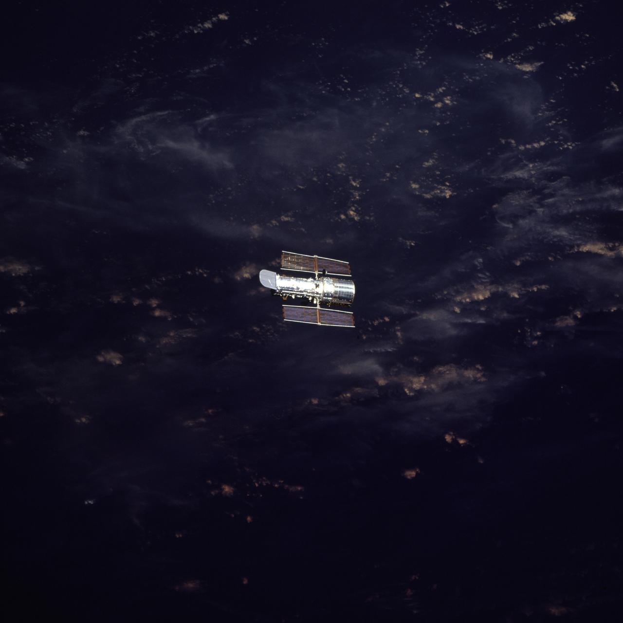 STS082-763-015 (11-21 Feb. 1997) --- Moving further and further away from the Space Shuttle Discovery, the Hubble Space Telescope (HST) is backdropped over clouds on Earth. This is the fifth in a series of post-release views recorded on 70mm film by the STS-82 crewmembers. Five space walks were performed by two pairs of astronauts who alternated days of Extravehicular Activity (EVA) to service the giant orbiting observatory.