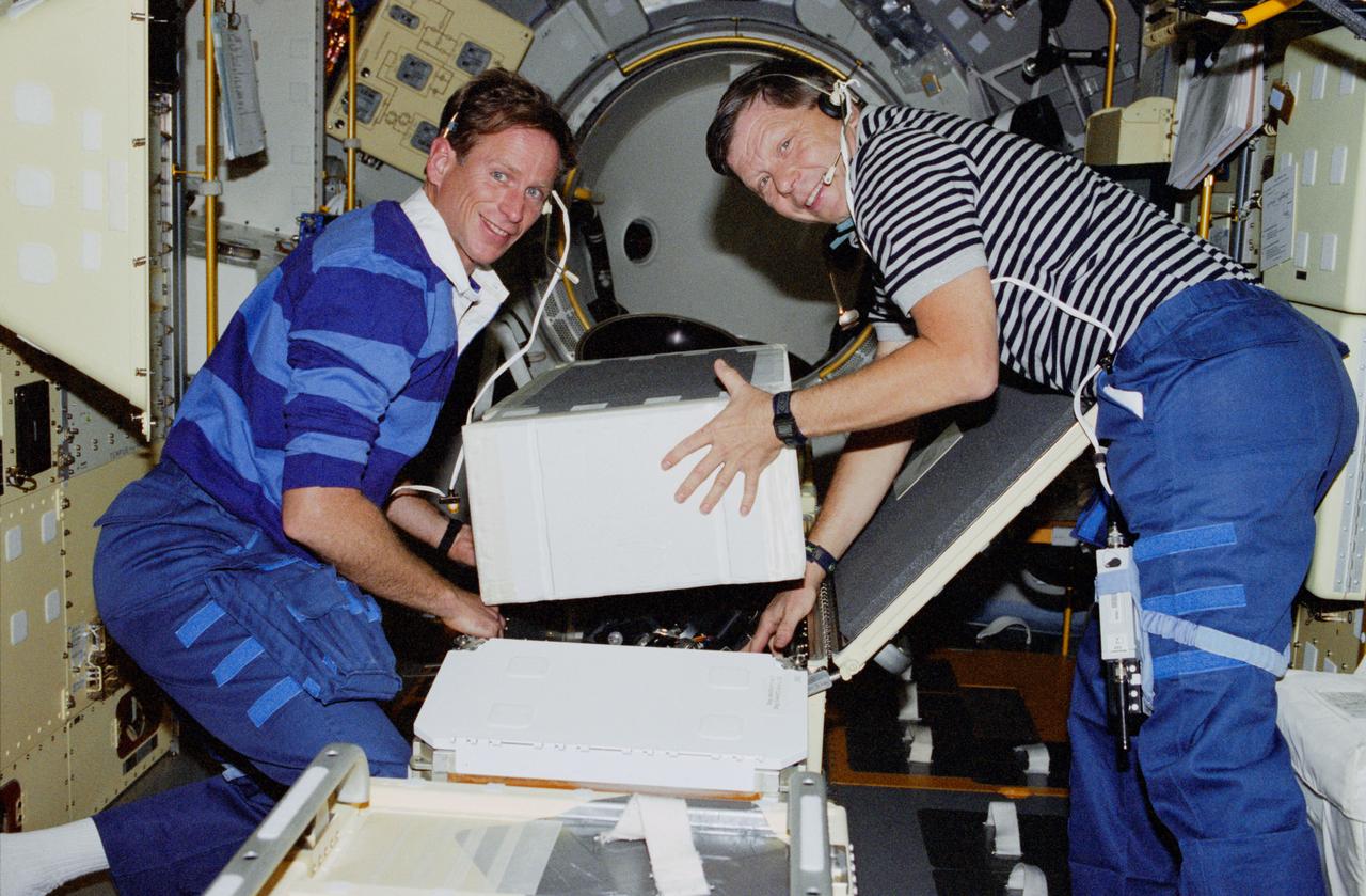 STS083-308-021 (4-8 April 1997) --- Payload specialist Roger K. Crouch and astronaut Michael L. Gernhardt, mission specialist, load boxes as they prepare to deactivate the Spacelab Science Module.  Crouch and Gernhardt, along with five other NASA astronauts and a second payload specialist supporting the Microgravity Sciences Laboratory (MSL-1) mission, were less than a fourth of the way through a scheduled 16-day flight when a power problem cut short their planned stay.