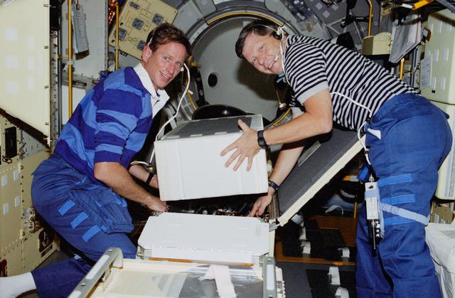 NASA image: Crouch and Gernhardt unpack items from Spacelab center aisle