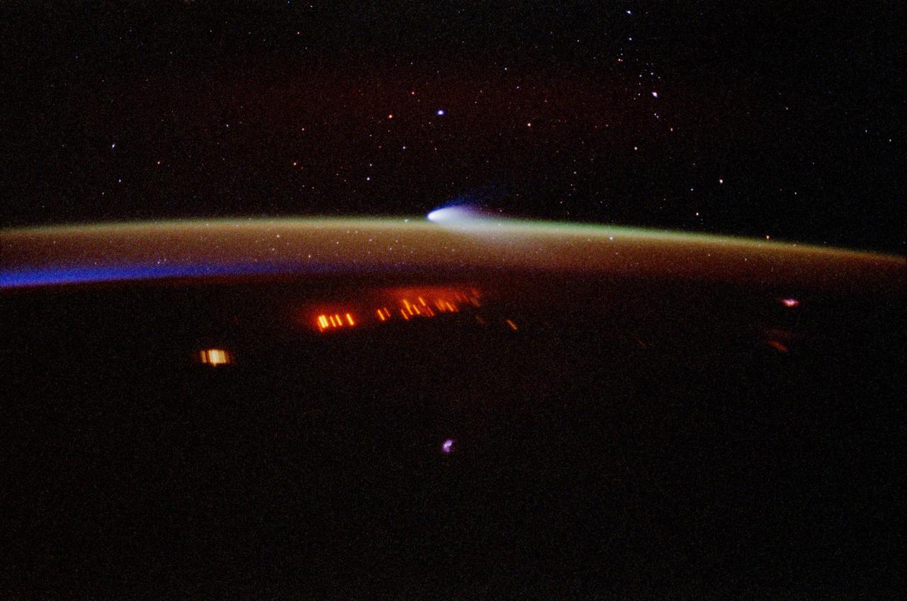 STS083-410-008 (4-8 April 1997) --- A 35mm camera was used to record this time-exposed image of Comet Hale-Bopp at sunset.  Note that stars show up in this image because of the more lengthy exposure time, whereas the celestial features do not show in the majority of Space Shuttle pictures focused on Earth and its horizon.  As another spin-off of the more lengthy time exposure, city lights and petroleum fires are seen as distorted streaks.