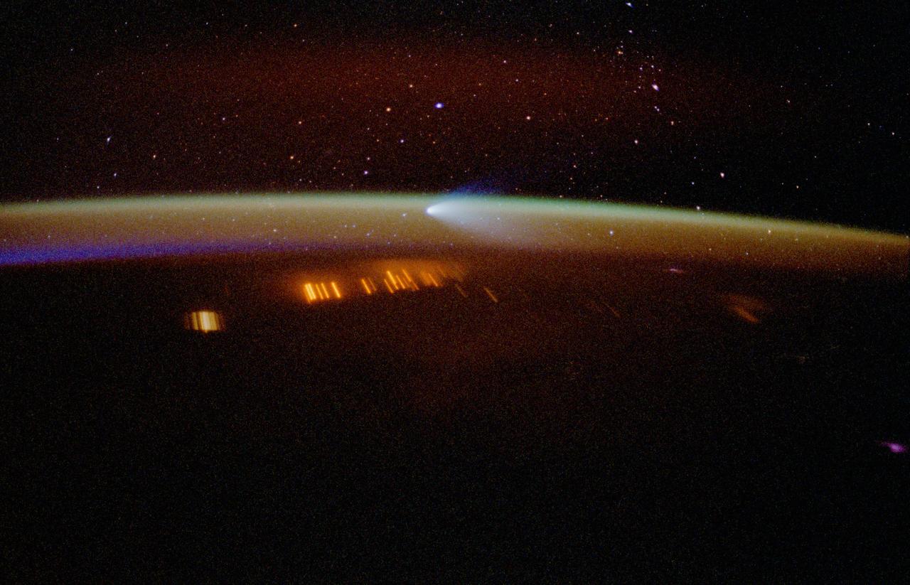 STS083-410-009 (4-8 April 1997) --- A 35mm camera was used to record this time-exposed image of Comet Hale-Bopp at sunset. Note that stars show up in this image because of the more lengthy exposure time, whereas the celestial features do not show in the majority of Space Shuttle pictures focused on Earth and its horizon. As another spin-off of the more lengthy time exposure, city lights and petroleum fires are seen as distorted streaks.