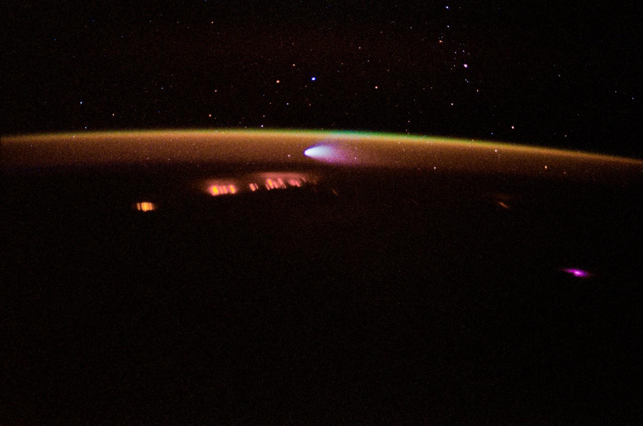 STS083-410-011 (4-8 April 1997) --- A 35mm camera was used to record this time-exposed image of Comet Hale-Bopp at sunset. Note that stars show up in this image because of the more lengthy exposure time, whereas the celestial features do not show in the majority of space shuttle pictures focused on Earth and its horizon. As another spin-off of the more lengthy time exposure, city lights and petroleum fires are seen as distorted streaks. Photo credit: NASA