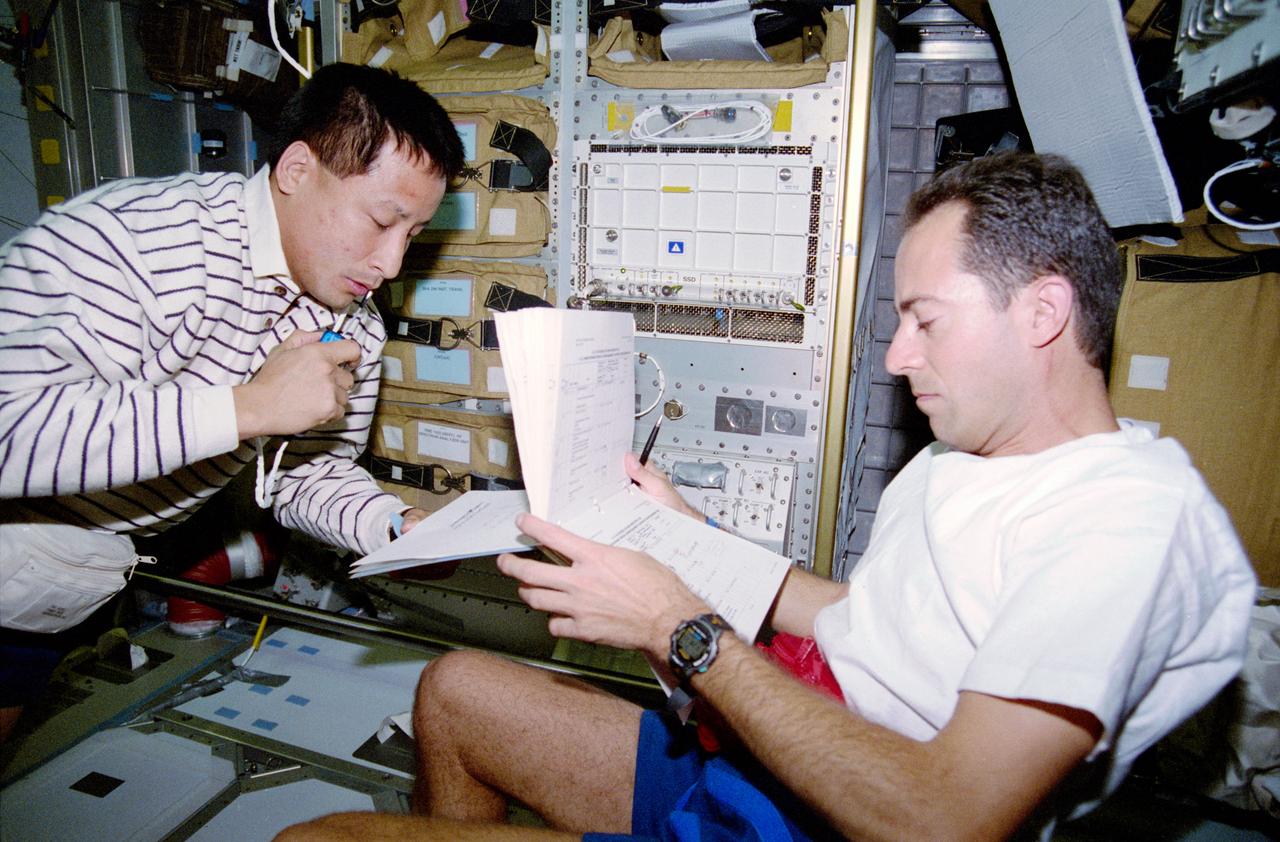 STS084-304-004 (15-24 May 1997) --- Astronaut Edward T. Lu (left) gets an early start on transfer operations in the Spacehab Double Module as he goes over an inventory checklist with astronaut Jean-Fran?ois Clervoy, payload commander. Later, almost three tons of supplies were transferred between the Space Shuttle Atlantis and Russia's Mir Space Station.