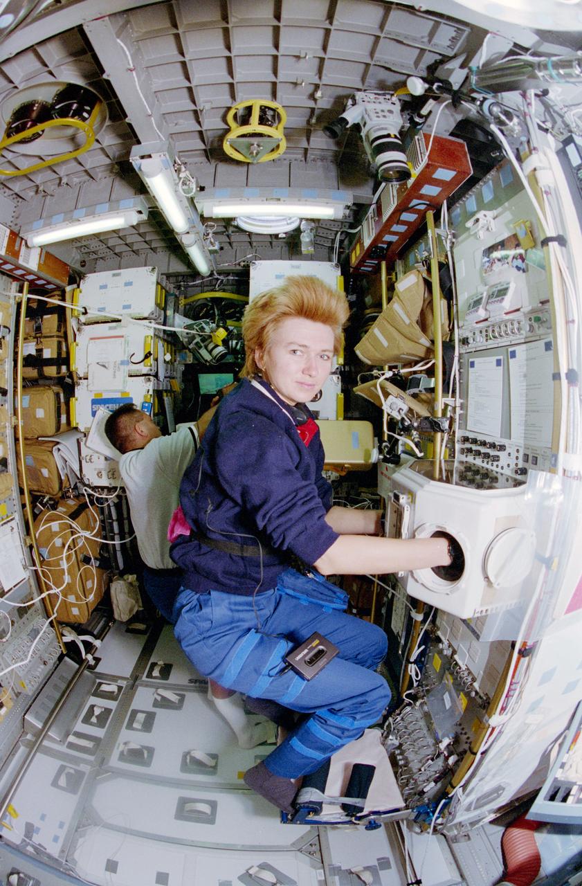 STS084-317-020 (15-24 May 1997) --- Elena V. Kondakova works in the Spacehab glovebox, aboard the Space Shuttle Atlantis, as Carlos I. Noriega, a fellow mission specialist, checks on an experiment in the background.