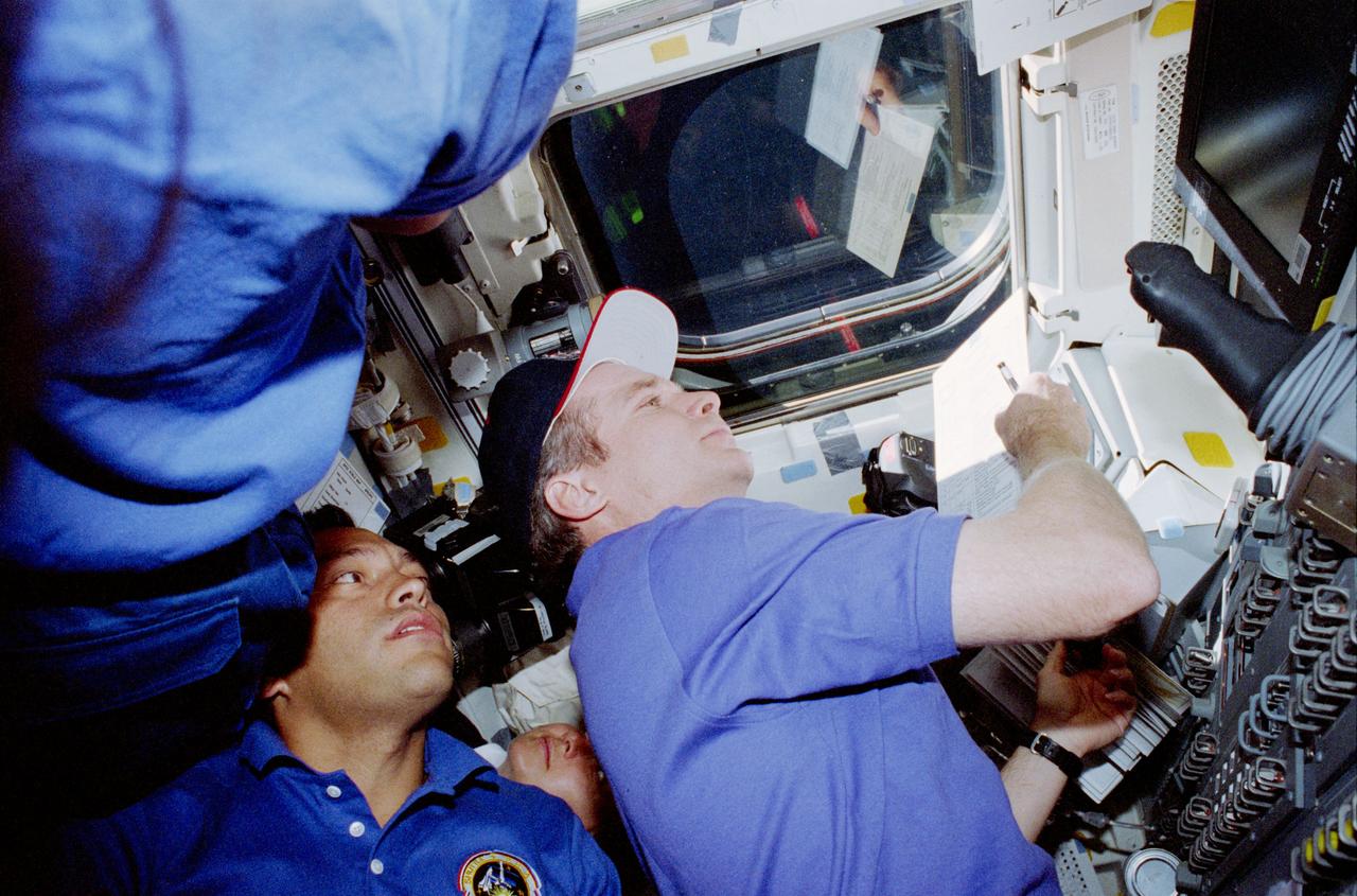 STS084-357-015 (15-24 May 1997) --- Astronaut Charles J. Precourt (right), STS-84 commander, controls the rate of the Space Shuttle Atlantis' approach to Russia's Mir Space Station during rendezvous operations. Carlos I. Noriega (left), Elena V. Kondakova (bottom center) and an unidentified crew member (far left) crowd into the scene -- typical of the busy rendezvous in-cabin scenarios on all Mir-Atlantis missions.