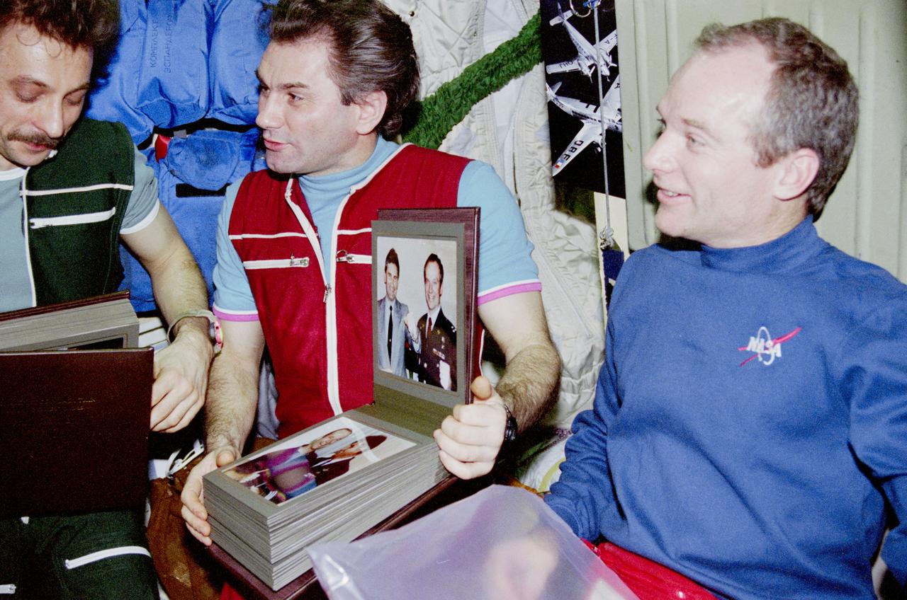 STS084-376-005 (15-24 May 1997) --- Onboard the Core Module of Russia's Mir Space Station, the American Space Shuttle commander exchanges gifts with the Mir-23 crew. Astronaut Charles J. Precourt has just handed two picture albums, documenting several months of interface between the Americans and Russians, to cosmonauts Aleksandr I. Lazutkin (left), flight engineer; and Vasili Tsibliyev, commander.