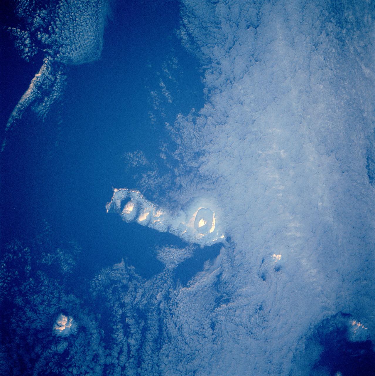 STS084-712-003 (15-24 May 1997) --- Early morning sun highlights the volcanic features on Onekotan Island which is one of several volcanic islands in the Russian owned Kurile Island chain. Onekotan lies just south of Kamchatka. Two volcanoes are active on the island -- the small island surrounded by a moat-like lake in the south (Tao-Rusyr caldera) last erupted in 1952, and the cone-shaped peak at the north end of the island, Nemo peak, erupted in 1938.