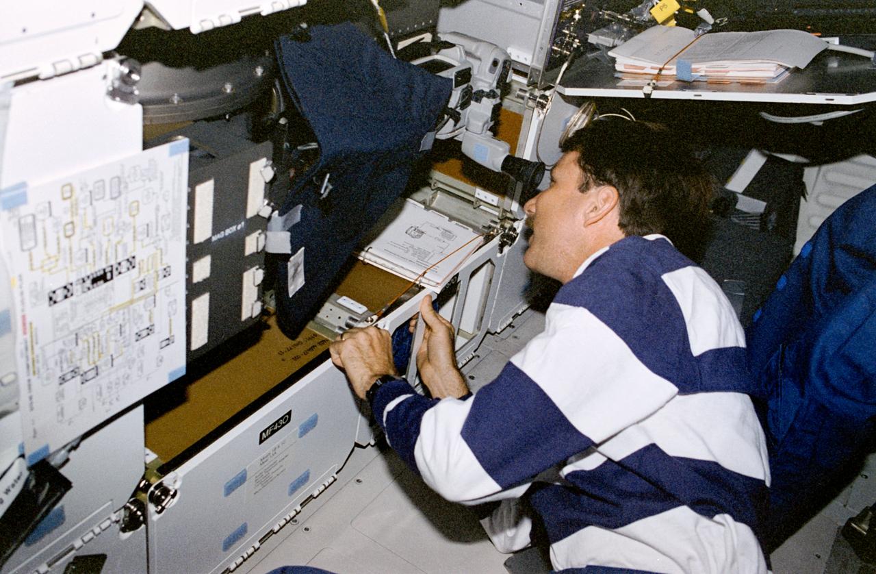 STS085-339-006 (7 - 19 August 1997) --- Astronaut Kent V. Rominger, pilot, checks on the Solid Surface Combustion Experiment (SSCE) on the mid-deck of the Space Shuttle Discovery. The experiment, which occupies the space of four lockers, consists of a Polymethyl Methacrylate (PMMA) fuel sample internally mounted in the center of a pressurized chamber. Two windows orthogonal to each other in the chamber wall allow viewing by a 16mm camera of the side edge and top of the PMMA sample.