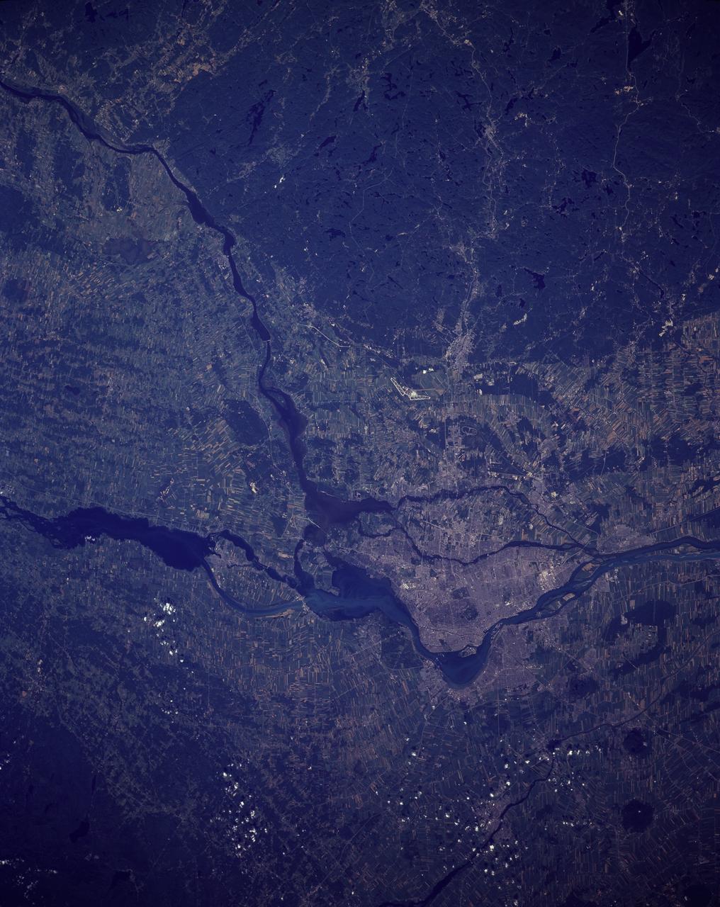 STS085-506-081 (7-19 August 1997) --- Montreal is a city on an island that grew up around the mountain -- in 1535 Jacques Cartier landed on an island in the St. Lawrence River and named a 233 meter-high mountain Mount Royal. It was not until 1642 that Ville Marie, founded by missionaries, would officially become the city of Montreal. The cityscape contrasts well with the farmland and natural forests in this summer view. Today Montreal is the largest city in the province of Quebec, and is the second most populous metropolitan area in Canada -- in 1991 the population was just more than one million in the city and 3,127,242 in the metropolitan area. While owing its early growth to the fur trade, the city is a leading producer of aircraft, chemical and pharmaceutical products, and is a major petroleum production center. Nearly half of Canada's .8 billion aerospace industry is located in the Montreal area. In the image captured by the astronauts, the lighter blue, wide river is the St. Lawrence. The city of Montreal is located on the Ile de Montreal to the northwest of the St. Lawrence river. The Ottawa River enters the St. Lawrence near the center of the view. Mirabel International Airport stands out well, on the north side of the city. The long, narrow strips of land in the image are indicative of French agricultural land use. The narrow ends of farmlands are oriented perpendicular to rivers so that more farmers will have access to water resources.