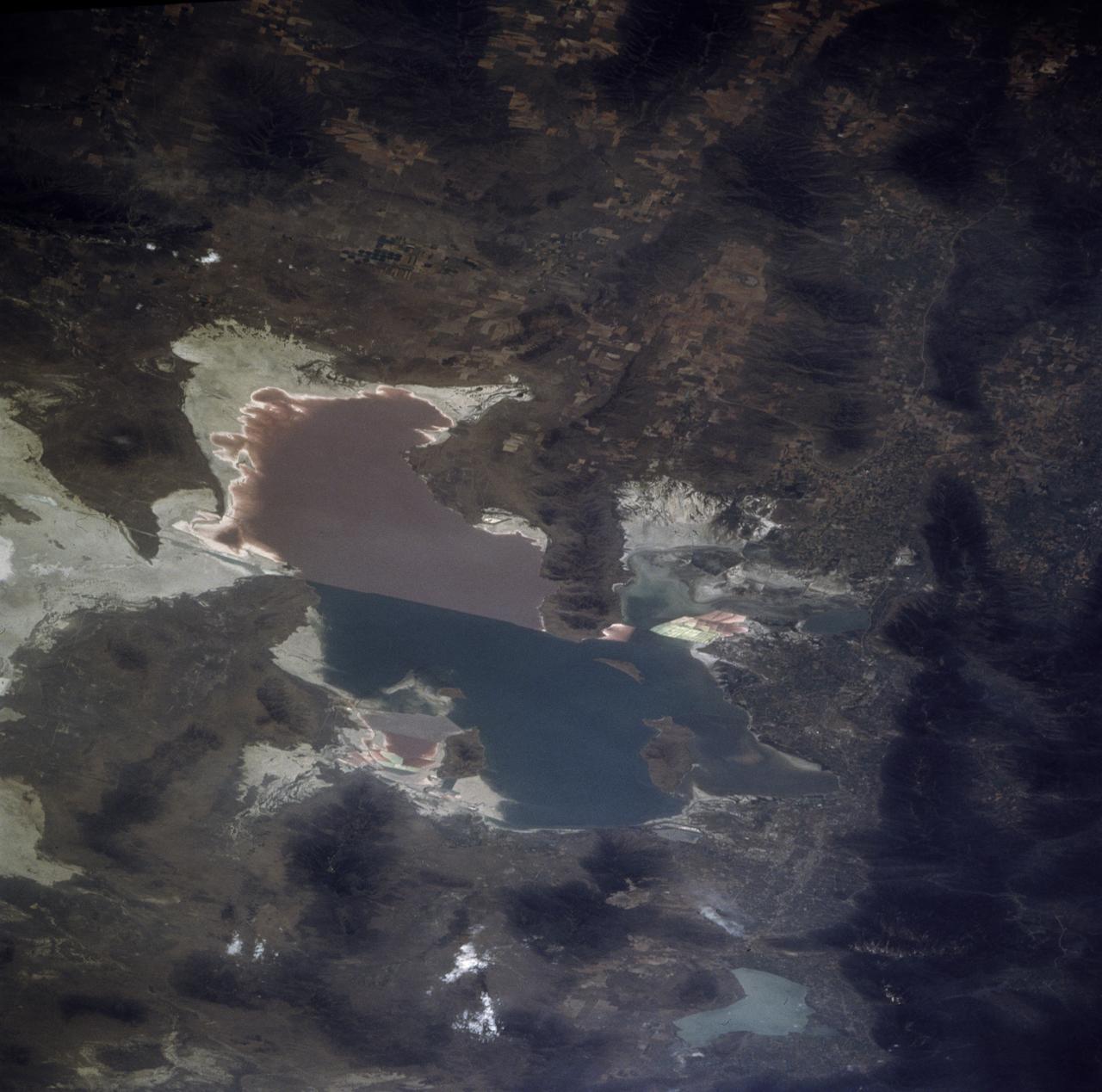 STS085-705-062 (7 - 19 August 1997) --- The Great Salt is one of the most saline inland bodies of water in the world and is the largest inland body of salt water in the Western Hemisphere. The lake is fed by three rivers (Bear, Weber and Jordon) and has no outlet. The water level varies with the amount of rainfall and evaporation in the basin. The distinct line across the center of the lake is the Lucin Cutoff. It is a 30 mile (48 kilometers), east-west causeway built in 1959 to support a rail line. The causeway connects the cities of Ogden and Lucin and affects the water level of the lake. Because the lake's main tributaries enter from the south, the water level of the southern section is several inches higher than that of the northern part. The Great Salt Lake's record high levels in the mid-1980's threatened the Lucin Cutoff, highways and sewage-treatment plants along the shore -- in 1987 pumps were installed that began draining some of the excess water into the Great Salt Lake Desert to the west. The resulting new body of water was called the Newfoundland Evaporation Basin -- it contains dissolved minerals, primarily sodium and chloride along with sulfate, magnesium, and potassium. The dissolved minerals, turbidity and microorganisms which can survive in saline water give the lake its varying colors. In this photo the north portion is dark red. The crew said that it looked like dirt when they first saw it. Crews can not remember the north portion ever looking so red -- it is usually a light blue color.