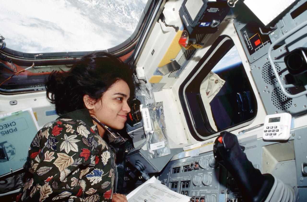 STS087-308-023 (19 November – 5 December 1997) --- Astronaut Kalpana Chawla, mission specialist, monitors the Extravehicular Activity (EVA) of fellow astronauts Winston E. Scott and Takao Doi from her temporary station on the Space Shuttle Columbia’s aft flight deck. Chawla controlled Columbia's Remote Manipulator System (RMS) at this station. Chawla (from her in-cabin post), Doi and Scott shared duties in two separate sessions of EVA during the 16-day United States Microgravity Payload (USMP) mission.