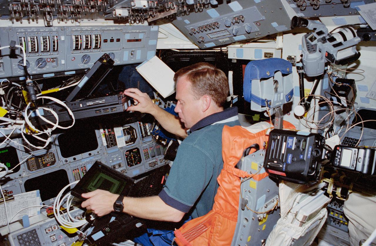STS087-319-015 (19 November – 5 December 1997) --- On the starboard side of the Space Shuttle Columbia's flight deck, astronaut Steven W. Lindsey, pilot, appears fully occupied with laptops to support flight operations for the 16-day mission in Earth-orbit. Several cameras and pieces of their supportive equipment have been temporarily stowed behind the pilot's station.