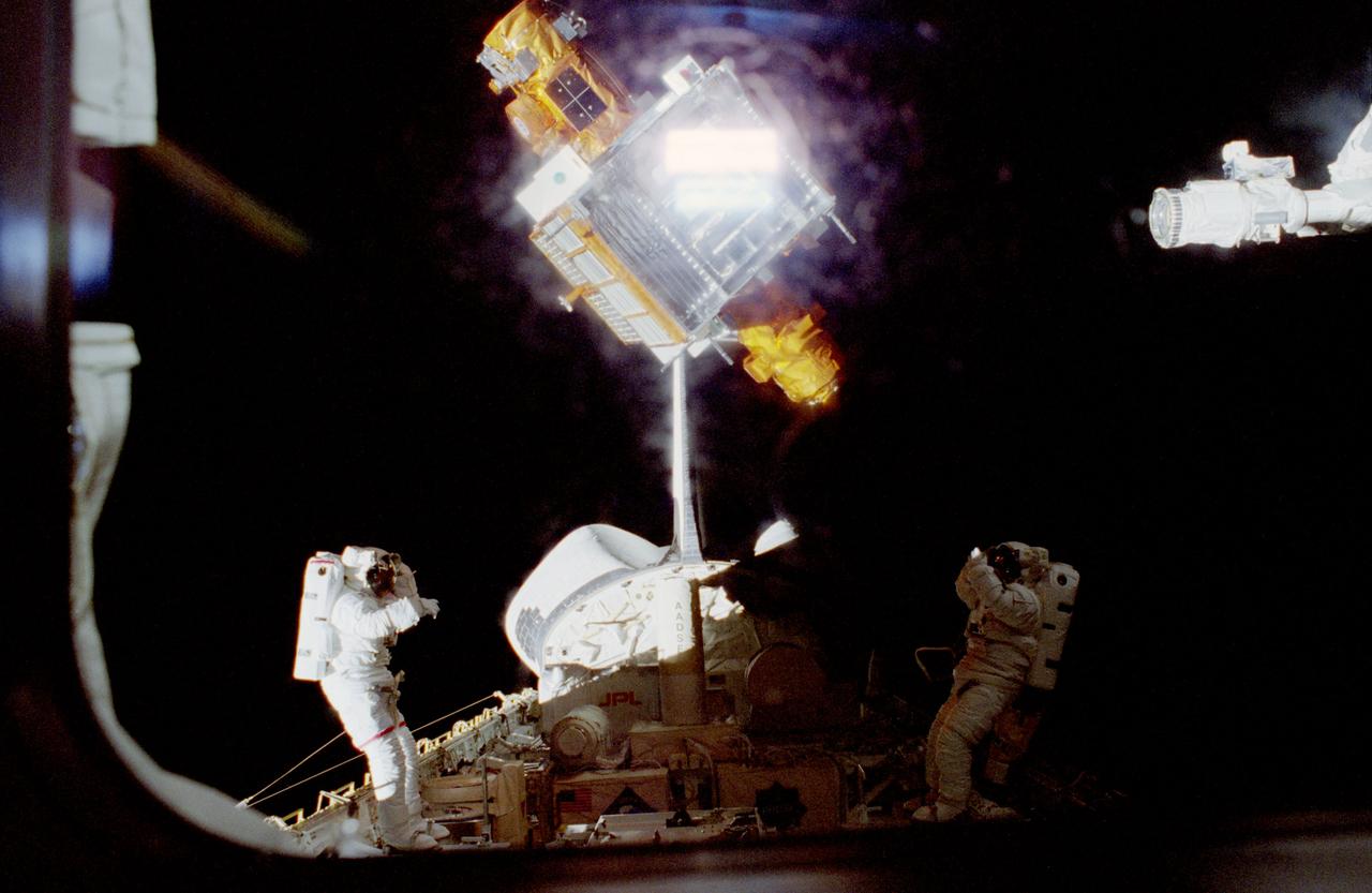 STS087-320-025 (19 November – 5 December 1997) --- Astronauts Winston E. Scott (left) and Takao Doi (partially obscured by his location in the dark shadows), await the right opportunity to grab onto the Spartan satellite.  Later, when the Space Shuttle Columbia had moved closer to Spartan, the two mission specialists were able to successfully grab the satellite manually and berth it in Columbia's cargo bay.  The end effector of Columbia's Remote Manipulator System (RMS), with its video camera recording the activities, is in the upper right corner.  Winston E. Scott was making his second space flight and his second extravehicular activity (EVA).  Takao Doi, an international mission specialist stationed at the Johnson Space Center (JSC), represents the Japan’s National Space Development Agency (NASDA).