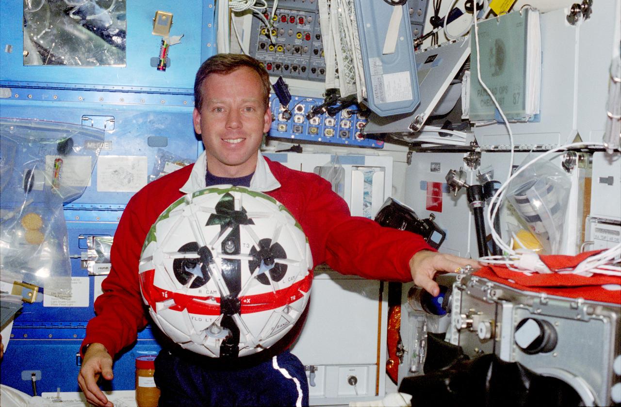 STS087-371-013 (19 November - 5 December 1997) --- On the Space Shuttle Columbia's mid-deck, astronaut Steven W. Lindsey proves that the Autonomous Extravehicular Activity Robotic Camera/Sprint (AERCam/Sprint) experiment is in fact bigger than a soccer ball, to which it is often erroneously compared for dimensional frame of reference, as he allows the Sprint to float near him. The AERCam is a prototype free-flying television camera that could be used for remote inspections of the exterior of the International Space Station (ISS). Later, astronauts Winston E. Scott and Takao Doi took the experiment outside for a brief test during the mission's second Extravehicular Activity (EVA). Lindsey, pilot, is standing with his back to the galley and his left hand on the microgravity glovebox, used extensively during the mission to support the United States Microgravity Payload (USMP-4) mission.