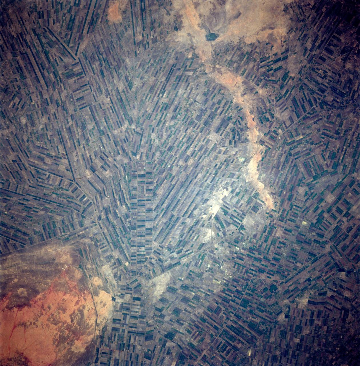 STS087-717-088 (19 November – 5 December 1997) --- Featured in this view are Sudan’s agricultural projects dependent on irrigation. Just southeast of the confluence of the Blue and White Nile rivers (and the city of Khartoum) is one of the largest irrigation projects in the world, known as the Gezira Scheme. The economy of Sudan is largely based on agriculture. The Gezira Scheme was begun by the British in 1925 and distributes water from the Blue Nile through canals and ditches to tenant farms lying between the Blue and White Nile rivers. Farmers cooperate with the Sudanese government and the Gezira Board. This network of canals and ditches is 2,700 miles (4,300 kilometers) long, and the irrigated area covers 2.5 million acres (1 million hectares). The main crop grown in this region is cotton. This picture is one of the 70mm Earth observations visuals used by the crew at its post flight presentation events.