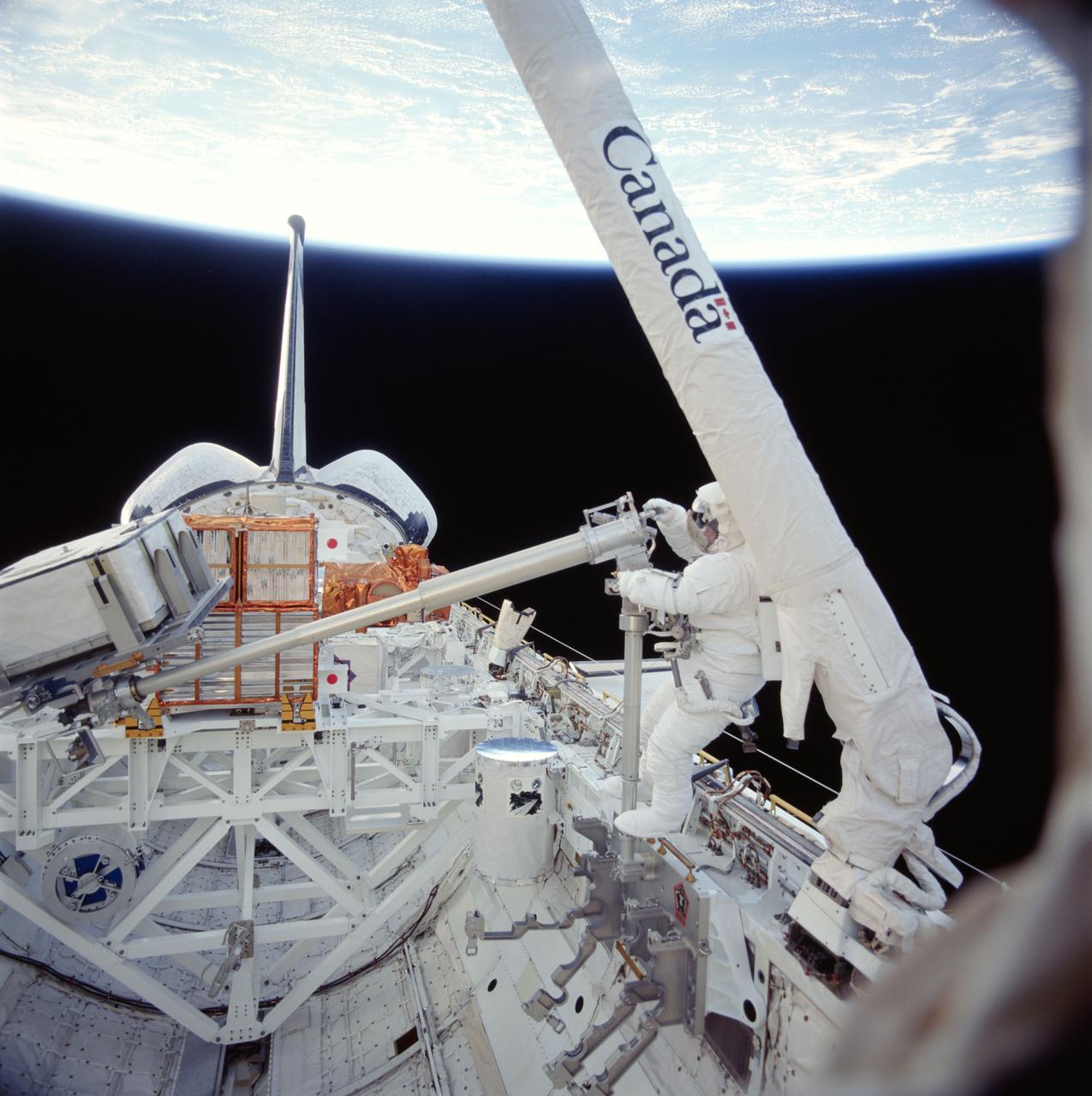 STS087-718-069 (19 November ? 5 December 1997) --- On the Space Shuttle Columbia's first ever spacewalk (EVA), astronaut Takao Doi works with a 156-pound crane carried onboard for the first time this trip of Columbia.  The crane's inclusion and the work with it are part of a continuing preparation effort for future work on the International Space Station (ISS).  The ongoing project allows for evaluation of tools and operating methods to be applied to the construction of the Space Station.  This crane device is designed to aid future spacewalkers in transporting Orbital Replacement Units (ORU), with a mass up to 600 pounds (like the simulated battery pictured here), from translating carts on the exterior of ISS to various worksites on the truss structure.  Earlier Doi, an international mission specialist representing Japan, and astronaut Winston E. Scott had installed the crane in a socket along the middle port side of Columbia's cargo bay for the evaluation.  The two began the crane operations, long ago manifest for this mission, after completing a contingency spacewalk to snag the free-flying Spartan 201 and berth it in the payload bay (visible in the background).