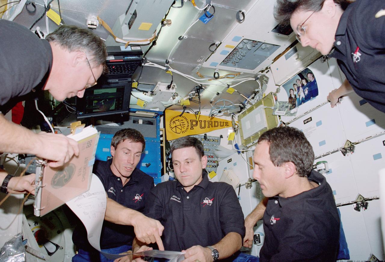 STS088-319-019 (4 - 15 DECEMBER 1998) --- A planning session on Endeavour's middeck includes all but one of the crew members. From the left are astronaut Jerry L. Ross, cosmonaut Sergei K. Krikalev, and astronauts Robert D. Cabana, James H. Newman and Nancy J. Currie. Missing from the scene is astronaut Frederick W. (Rick) Sturckow, who took the photo.