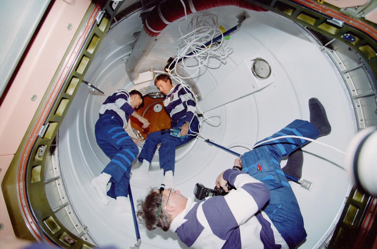 STS088-322-035  (4 - 15 DECEMBER 1998) --- Three STS-88 crew members are pictured in one of two Pressurized Mating Adapters (PMA) connected to the Unity and Zarya modules.  Taking pictures in the foreground is astronaut Jerry L. Ross, mission specialist.  Others are astronaut Robert D. Cabana (left), mission commander, and cosmonaut Sergei K. Krikalev, mission specialist representing the Russian Space Agency (RSA).