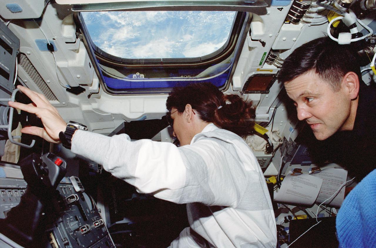 STS088-335-015 (4-15 Dec. 1998) --- Astronauts Nancy J. Currie, mission specialist, and Robert D. Cabana, commander, are busy on the flight deck of the Earth-orbiting Space Shuttle Endeavour.  Currie is working the controls of the Remote Manipulator System (RMS) arm, while Cabana observes.  The crew used the RMS for docking and extravehicular activity (EVA) support during the mission.  At mission?s end, the connected United States-built Unity Module (Node 1) and the Russian-built FGB Module (Zarya) were released in Earth-orbit.
