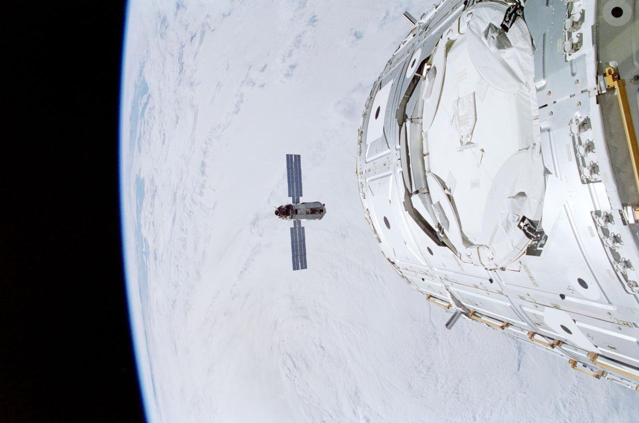 STS088-341-015 (6 Dec. 1998) --- Backdropped against a blanket of heavy cloud cover, the Russian-built FGB, also called Zarya, approaches the Space Shuttle Endeavour and the U.S.-built Node 1, also called Unity (foreground).  Inside Endeavour's cabin, the STS-88 crew readied the remote manipulator system (RMS) for Zarya capture as they awaited the rendezvous.
