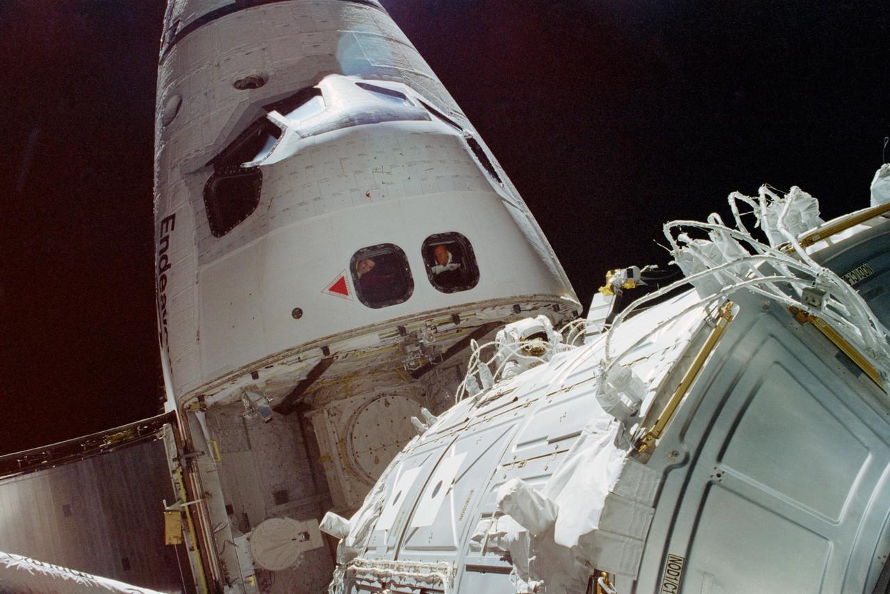 STS088-352-034 (4-15 Dec. 1998) --- This scene photographed from the top of Node 1 shows the nose of the Space Shuttle Endeavour, during one of three space walks.  Astronaut James H. Newman, mission specialist (frame center), was joined by astronaut Jerry L. Ross, mission specialist (out of frame), for the extravehicular activity (EVA) to ready for release the recently-joined Russian-built Zarya Module (FGB) and the United States-built Unity (Node 1) Module.  Fellow crew members Robert D. Cabana, commander (left window), and Frederick W. ?Rick? Sturckow, pilot, observe the EVA through aft flight deck overhead windows at left center.