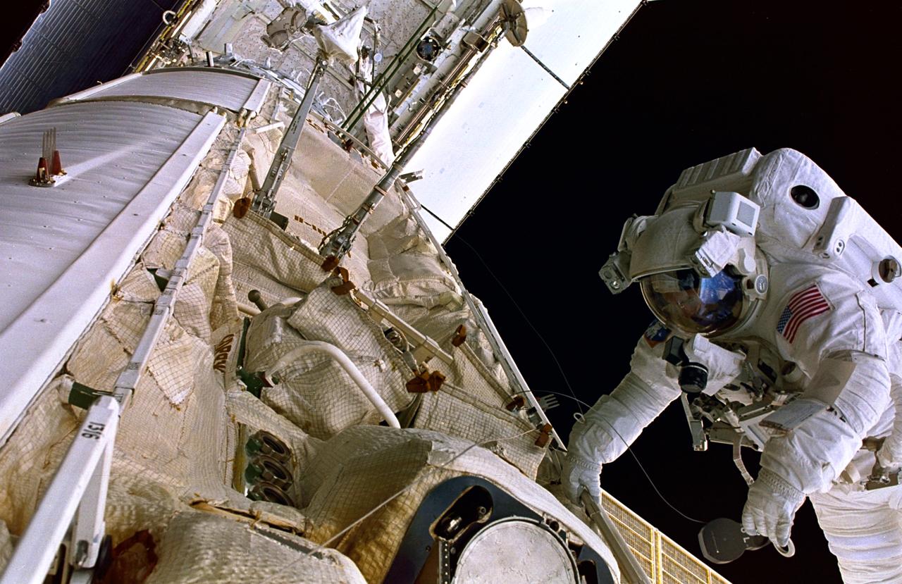 STS088-353-006 (4 -15 Dec. 1998) --- Astronaut James H. Newman, mission specialist, holds onto a handrail on Zarya while conducting a space walk at the top of the Unity-Zarya stack in the cargo bay of the Earth-orbiting Space Shuttle Endeavour. The open payload doors and part of the cargo bay, including the Ku-band antenna, are seen in upper left.