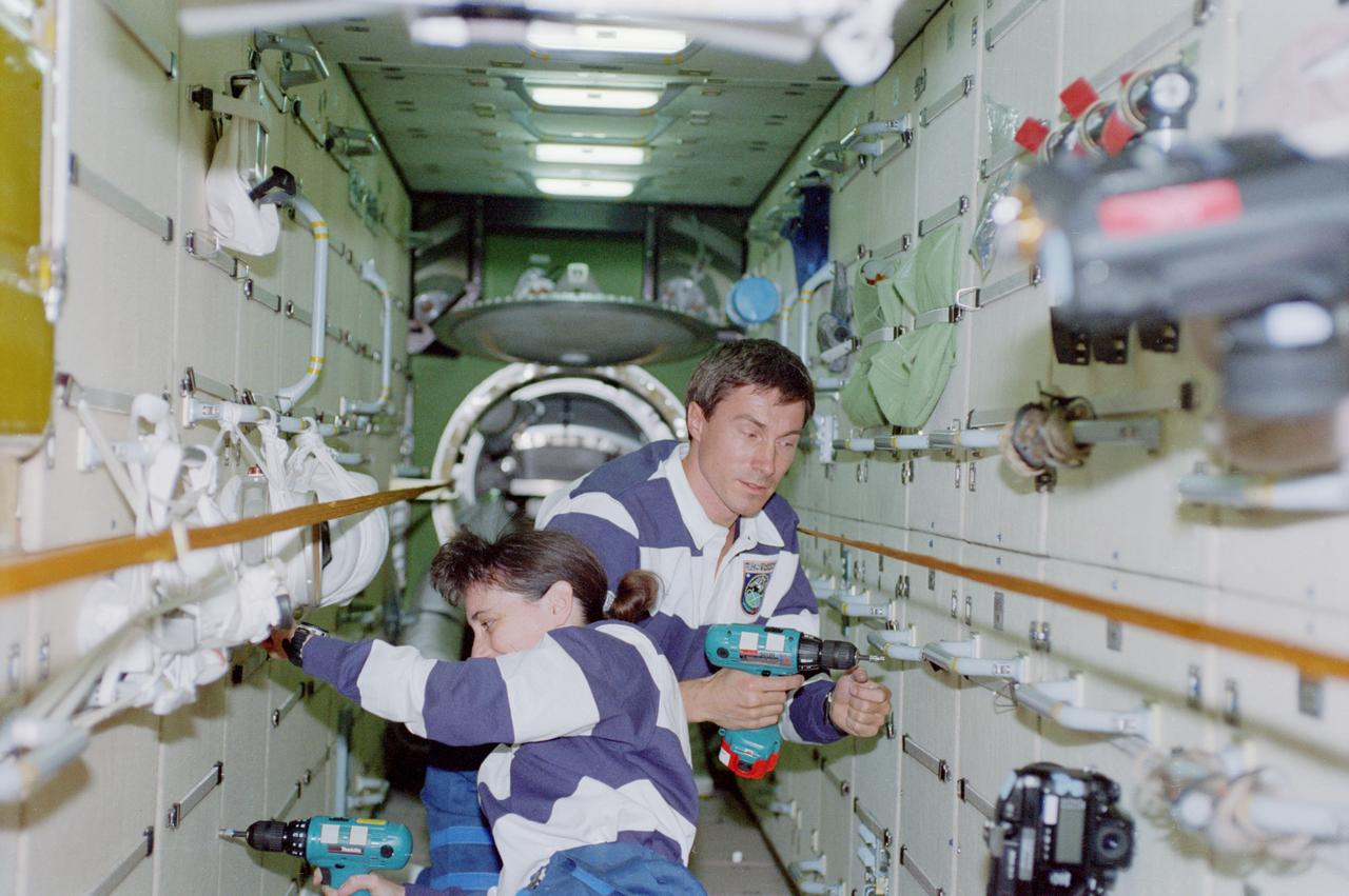 STS088-357-011 (4-15 Dec. 1998) --- Astronaut Nancy J. Currie, mission specialist, and cosmonaut Sergei K. Krikalev, mission specialist representing the Russian Space Agency (RSA), work in the FGB or Zarya Module of the International Space Station (ISS).  The two are using battery powered tools to extract bolts.
