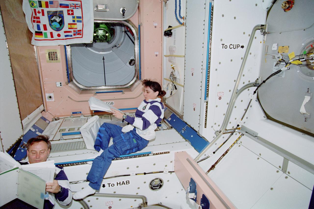STS088-357-020 (4-15 Dec. 1998) --- Astronauts Jerry L. Ross and Nancy J. Currie, both mission specialists, check procedures list prior to performing a variety of tasks in the United States-built Node 1 or Unity Module.  The hatchway in upper left corner accesses the Russian-built FGB or Zarya Module, which had earlier been retrieved with the aid of the Canadian-built Remote Manipulator System (RMS) and linked with Unity.