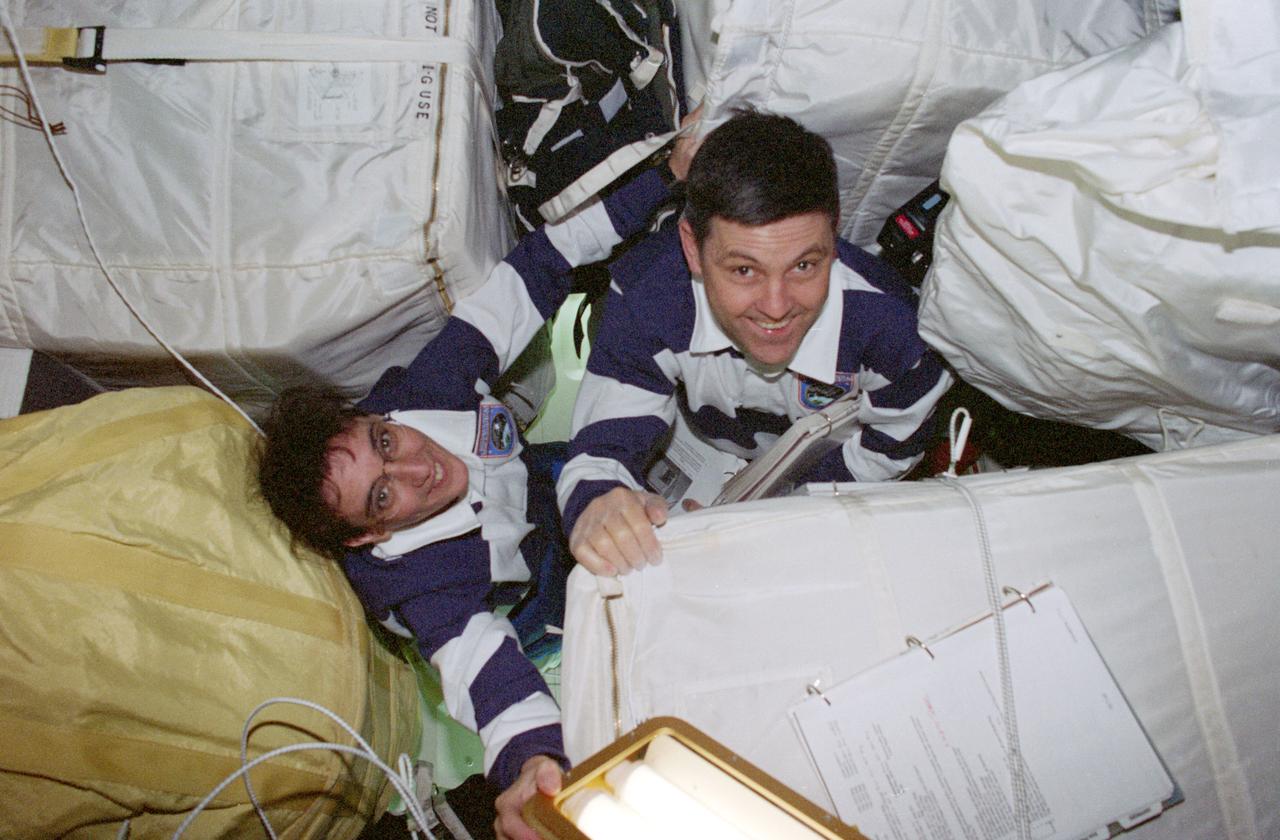 STS088-370-028 (4-15 Dec. 1998) --- Astronauts Nancy J. Currie, mission specialist, and Robert D. Cabana, commander, are surrounded by bags of supplies and equipment on the Space Shuttle Endeavour?s middeck.  The crew was in the process of readying the docked Unity and Zarya Modules for International Space Station (ISS) duty.