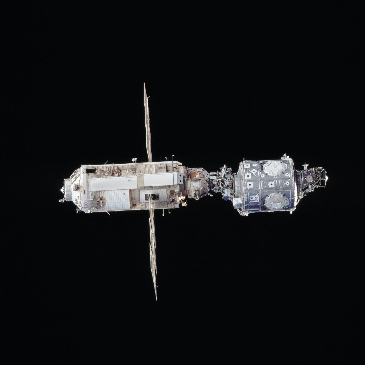 STS088-703-019 (4-15 Dec. 1998) --- The U.S.-built Unity connecting module (bottom) and the Russian-built Zarya module are backdropped against the blackness of space in this 70mm photograph taken from the Space Shuttle Endeavour. After devoting the major portion of its mission time to various tasks to ready the two docked modules for their International Space Station (ISS) roles, the six-member STS-88 crew released the tandem and performed a fly-around survey of the hardware.