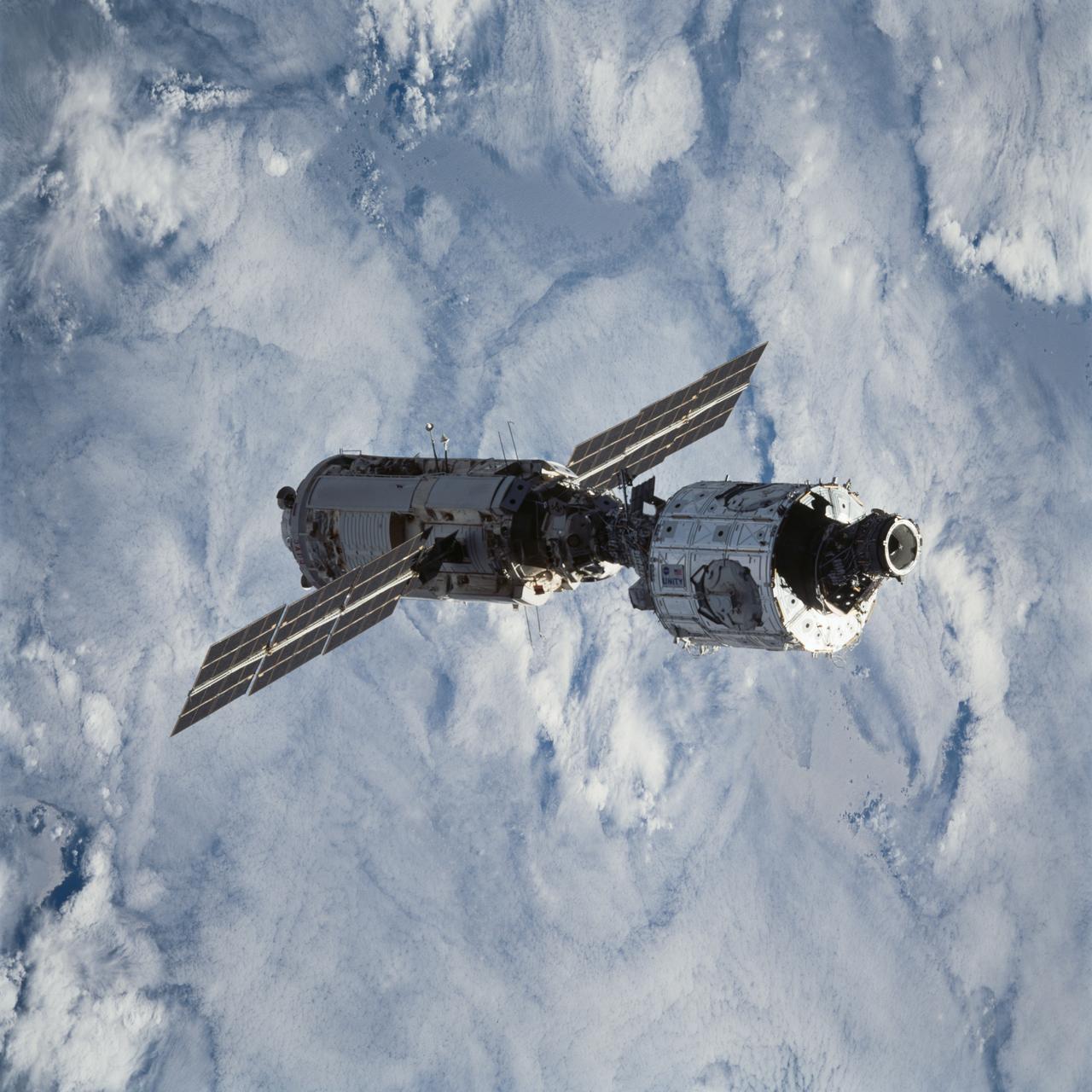 STS088-703-032 (4-15 Dec. 1998) --- Blanketing clouds form the backdrop for this 70mm scene of the connected Zarya and Unity modules after having been released from Endeavour's cargo bay a bit earlier.  Six crew members, who had earlier spent the majority of their on-duty mission time working on the tandem of space hardware, watched the joined modules from Endeavour in a survey and fly-around mode.