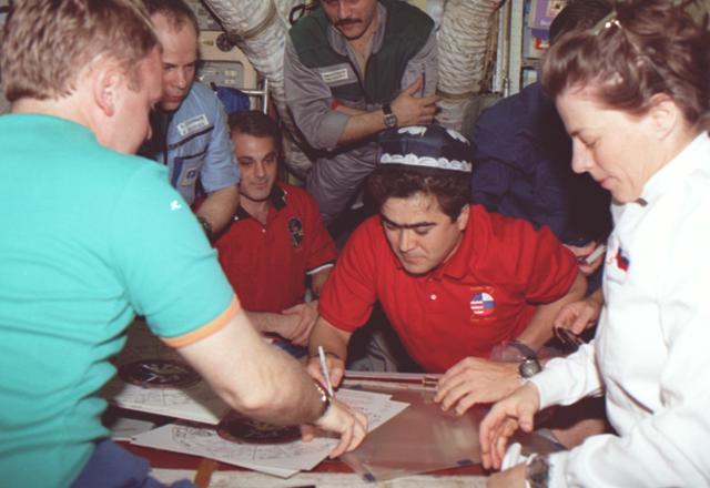 STS089-335-016 (22-31 Jan. 1998) --- Salizhan S. Sharipov (center) signs his name on a long-lived Mir roster on the Base Block of Russia's Mir Space Station, while Mir and shuttle crew members look on.  From the left are Andrew S. W. Thomas (back to camera), Anatoliy Y. Solovyev, David A. Wolf, Pavel V. Vinogradov, Joe F. Edwards Jr., (partially obscured) and Bonnie J. Dunbar.  Sharipov, representing the Russian Space Agency (RSA), is a mission specialist on the STS-89 crew. Photo credit: NASA