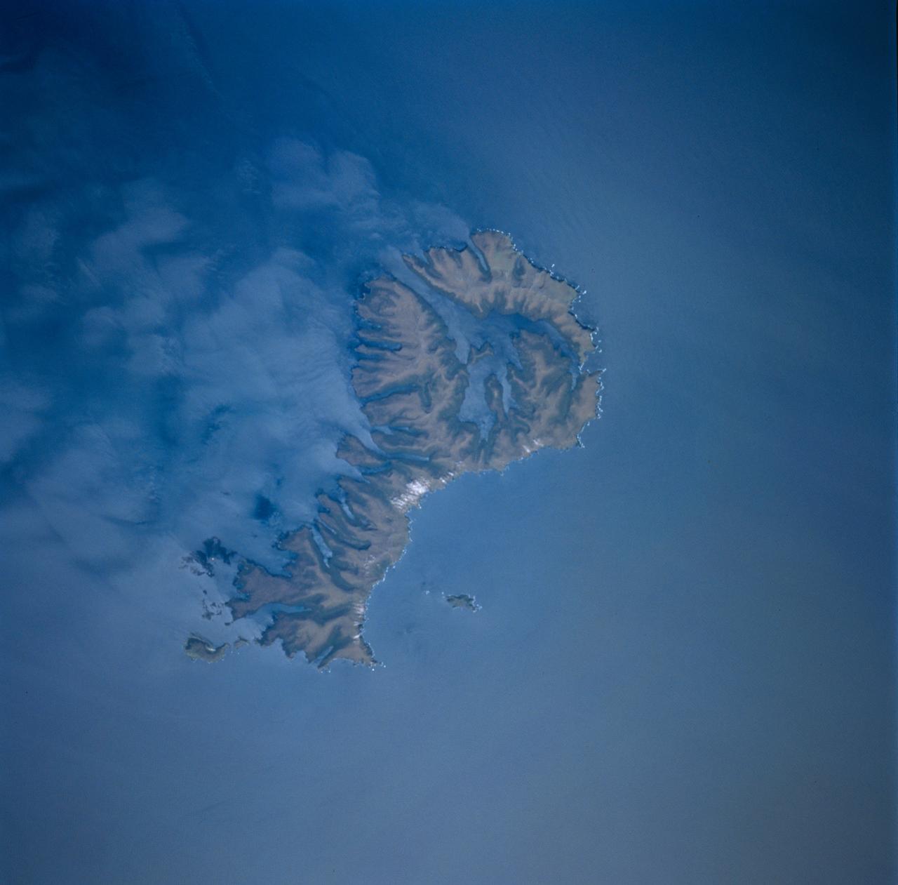 STS089-743-004 (22-31 Jan. 1998) --- This picture showing Auckland Island, New Zealand was photographed with a 70mm handheld camera from the Earth-orbiting space shuttle Endeavour.  A spectacular occurrence of internal waves in the ocean is visible in the wake of the island.  These waves can be generated by currents or, in some cases, wind across the island.  In this case, the observation was that these waves were visible after the sunglint disappeared, suggesting current generated effects.  If so, the circum-polar current that moves west-east around Antarctica would generate the scalloped appearance in the water east of the island.  There is characteristically very little surface expression to these waves so they would not be noticed by a ship in this region.  Fundamental processes of oceanic circulation and interaction are poorly understood.  These shots help oceanographers model the dynamics of the open ocean and work out mixing models for ocean layer and ocean-air interaction (important for modeling CO2 budget, for example).  The long linear valleys and bays have been excavated by glaciers cutting into this long-extinct volcano.  This island is located on the submerged Campbell Plateau, which is an area almost as large as the exposed land of South Island, New Zealand.  Scientists report that the plateau was submerged when New Zealand, Antarctica and Australia separated "around 75 million years ago."  This could be viewed as one of the tallest mountains on the plateau.  Usually the weather in this area is bad so this photo opportunity was considered a "great catch." Photo credit: NASA