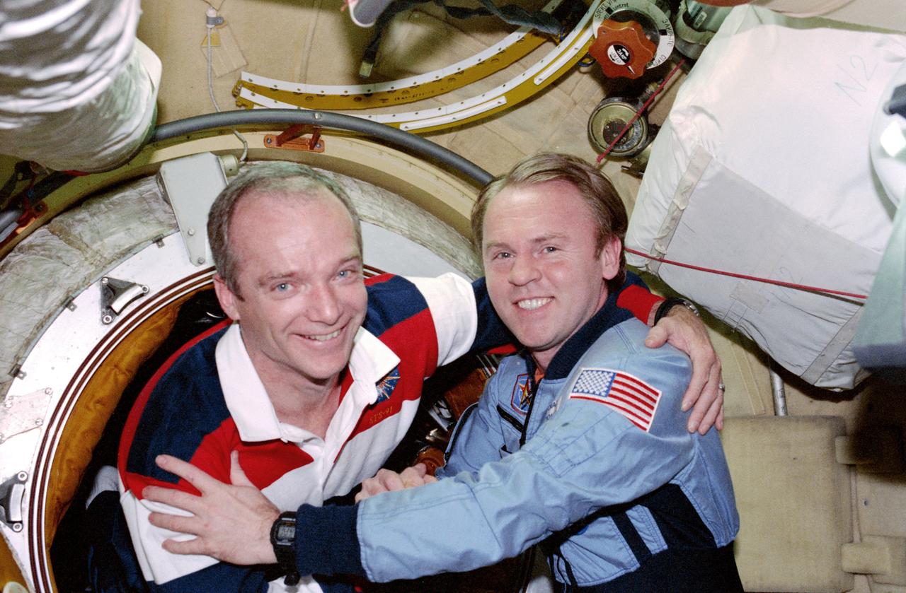 STS091-379-015 (2-12 June 1998) --- Astronauts Charles J. Precourt (left) and Andrew S.W. Thomas reunite moments after hatch opening.  Precourt, STS-91 mission commander, was joined on the visit of a Space Shuttle Discovery to Russia's Mir space station by four other astronauts and a Russian cosmonaut.  Thomas, at the time of the picture, was  a member of the Mir-25 crew.  He later returned to Earth with Precourt and the rest of the STS-91 crew.