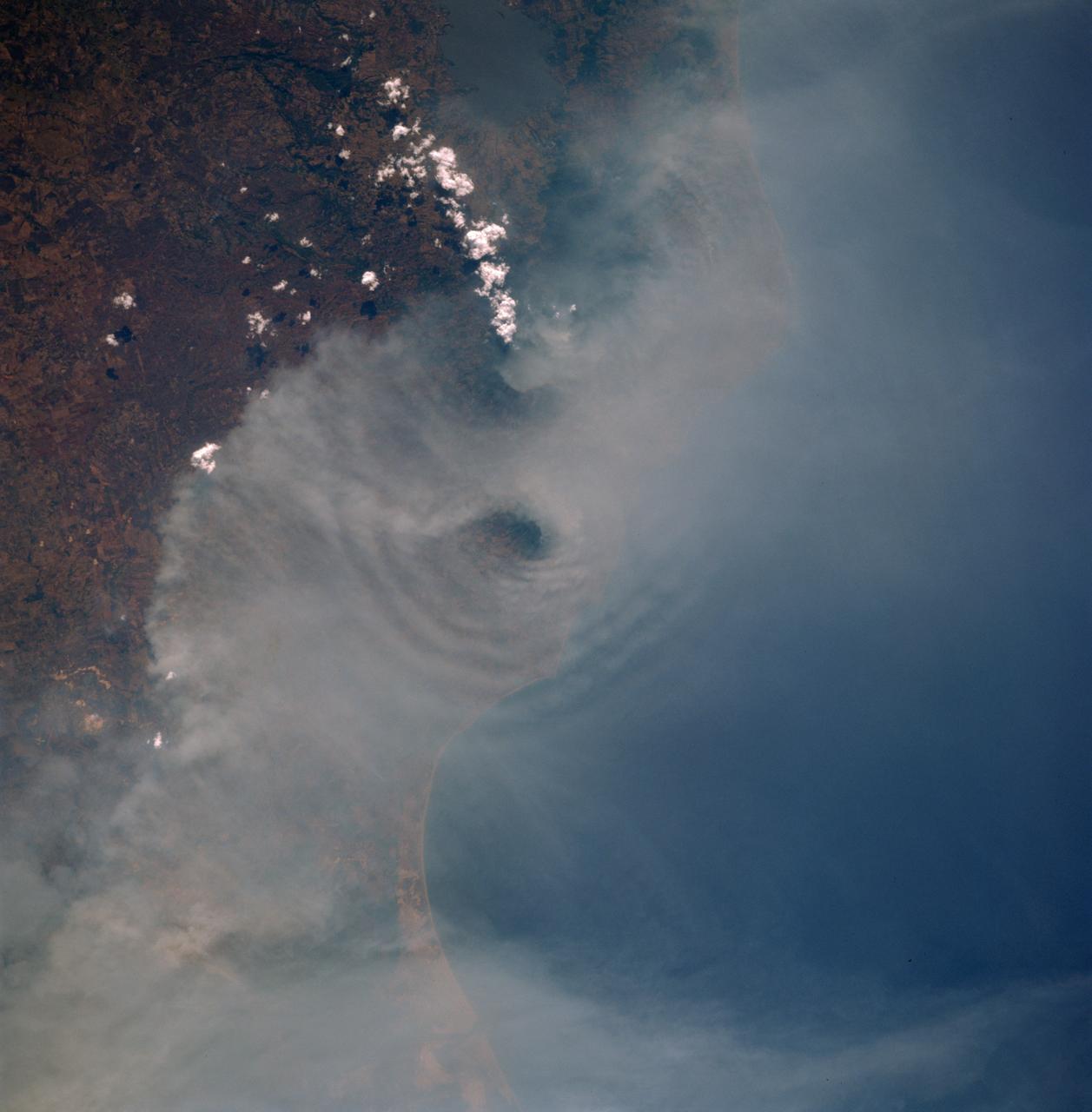 STS091-725-088 (2-12 June 1998)--- In this 70mm picture photographed during one of Discovery's passes over Mexico, waves generated by the volcanic peaks are seen as the wind carrying the smoke moves by the peaks. Along the coast of the Bay of Campeche, the fires burn around the peak of the Cerro San Martin (5,577 feet), which is west and higher than the peak with the waves around it. Lago Catemaco is on the west, center edge of the photo. Fires across Mexico and Central America created heavy smoke plumes for a few weeks in May and June, 1998. The smoke circulated around a high pressure system over the Gulf of Mexico and brought thick smoke and soot to the south central United States. Scientists are looking at burning regions like this around the world to study the smokes affect on the albedo or the reflectance of the suns rays and how it may influence our world's climate.