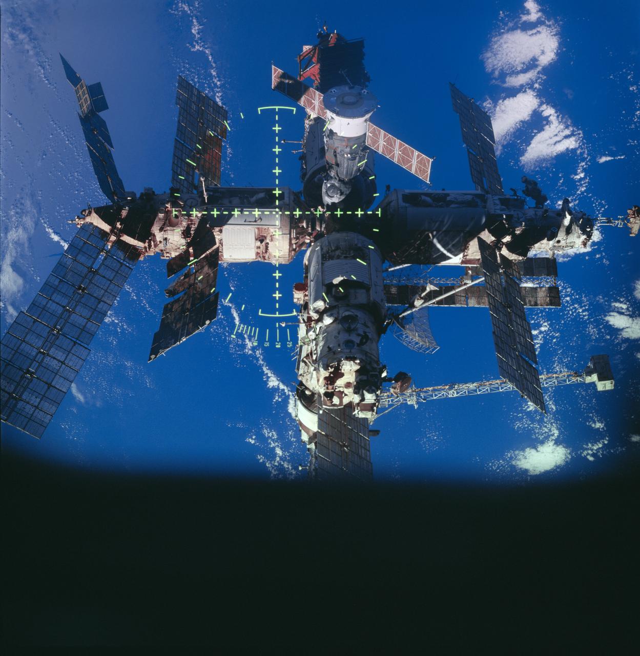 STS091-727-059 (2-12 June 1998) --- White clouds and blue ocean waters form the backdrop for this view of Russia's Mir space station during a post-undock  fly-around by the Space Shuttle Discovery, from which this 70mm frame was taken.  The markings in the photo are those of the Crew Optical Alignment Sight (COAS), an important instrument used normally for rendezvous and docking maneuvers.  The STS-91/Mir-25 docking marked the final scheduled link-up between Mir and members of the NASA Space Shuttle fleet.
