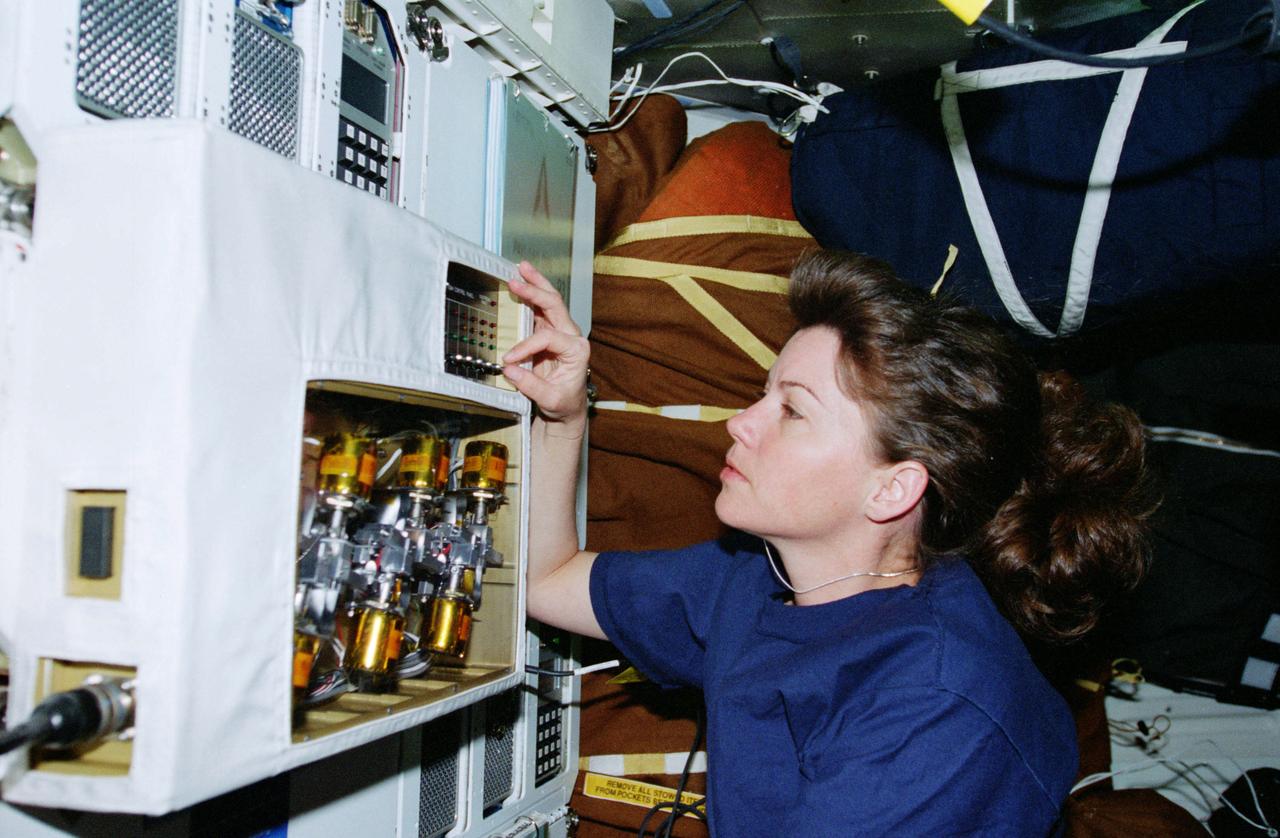 STS093-321-029 (22-27 July 1999) --- Astronaut Catherine G. Coleman, mission specialist, checks the Light Weight Flexible Solar Array Hinge (LWFSAH) experiment on the mid deck of the Earth-orbiting Space Shuttle Columbia.